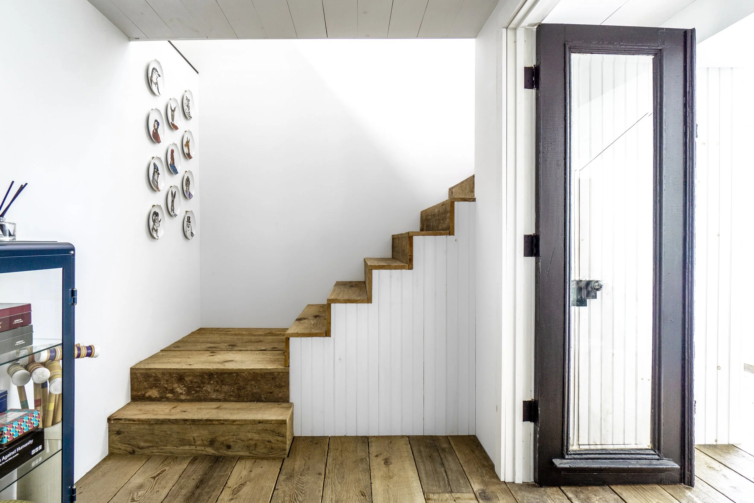 Minimal wood staircase with white paneling and rustic wood treads.