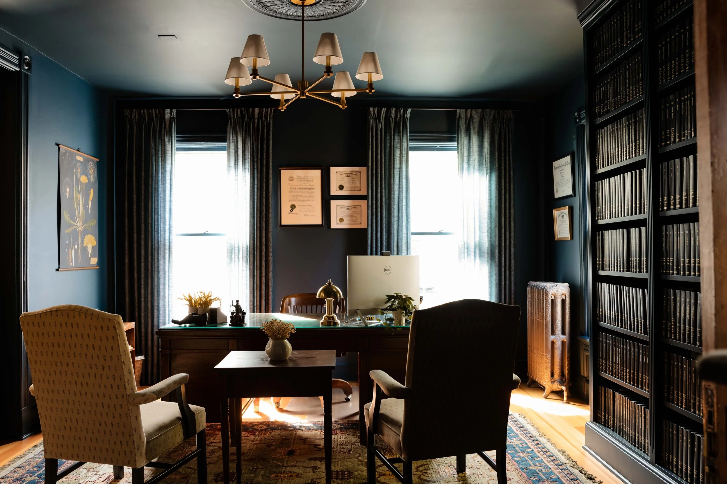 Principal office with brass chandelier, vintage desk, and floor-to-ceiling law book shelving