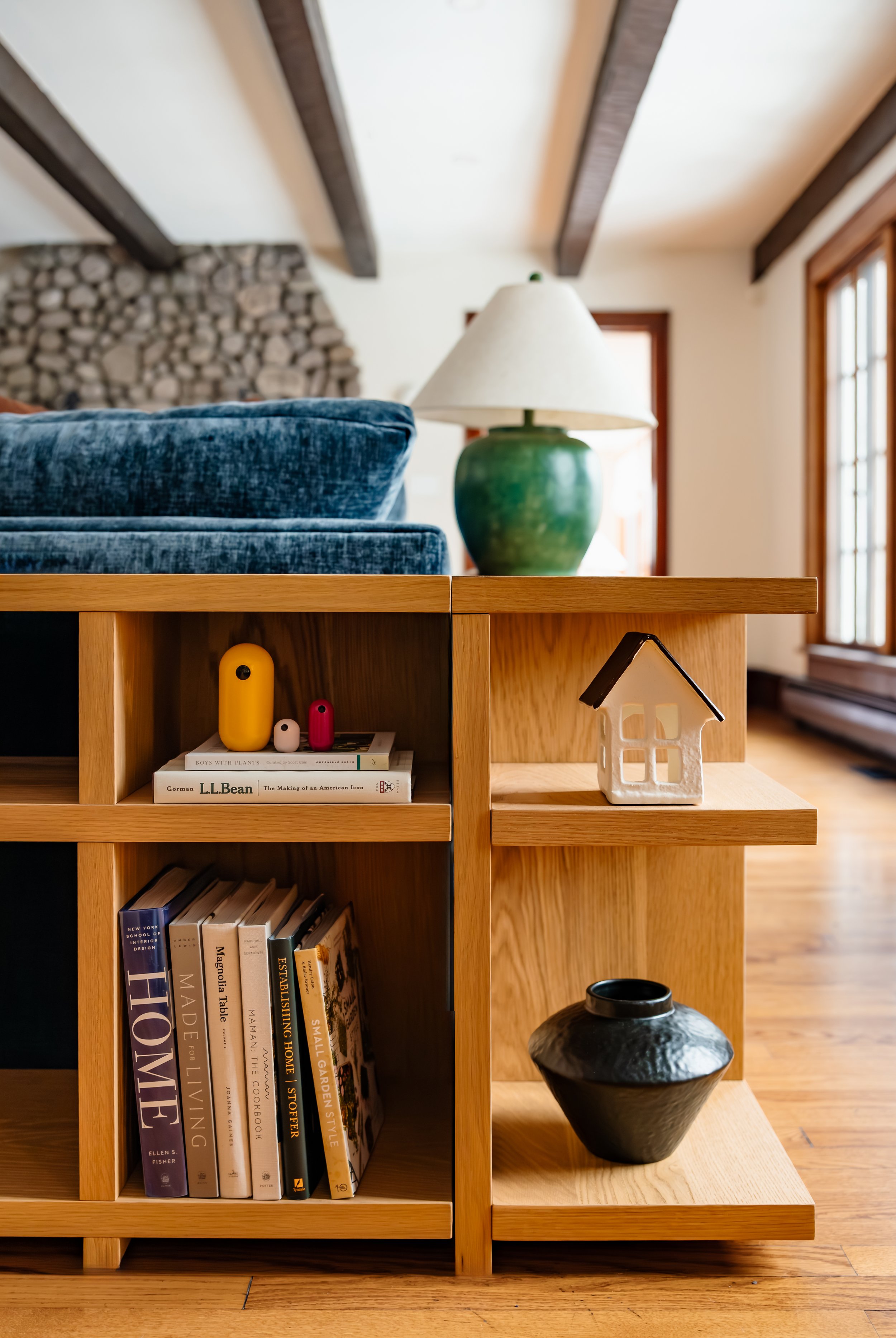 Oak shelving detail styled with books, ceramics, and decor behind the sofa.