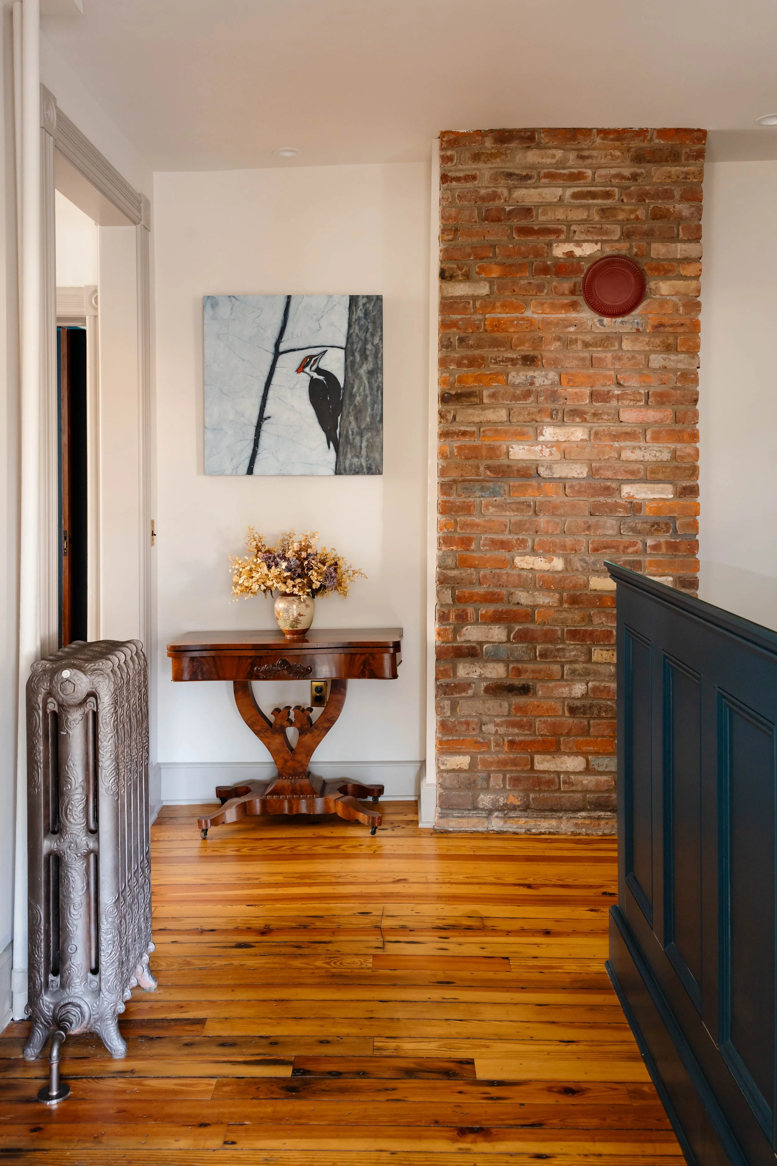 Exposed brick chimney and antique console table in renovated professional office