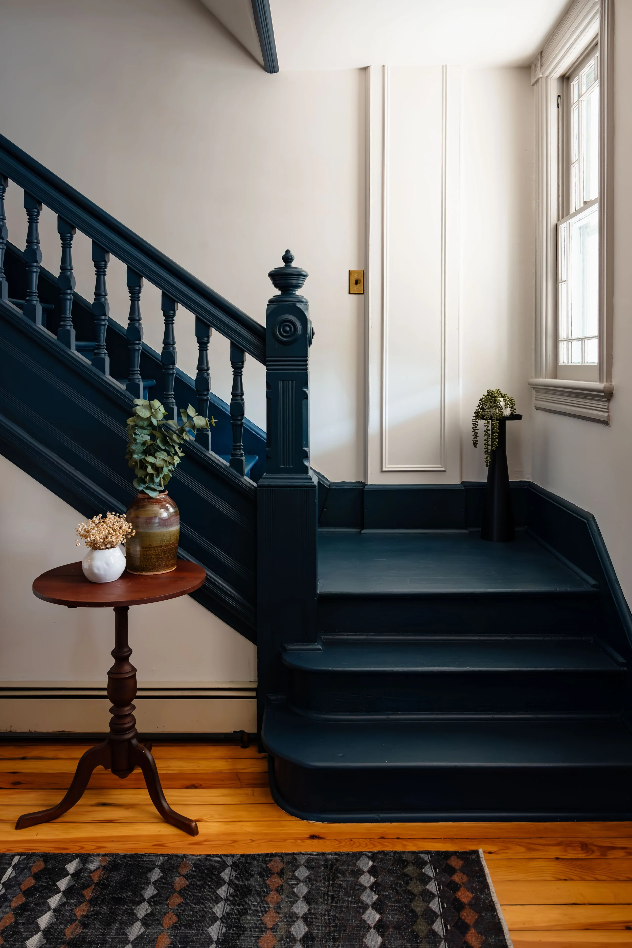 Close-up of painted wood staircase with turned balusters and original pine flooring