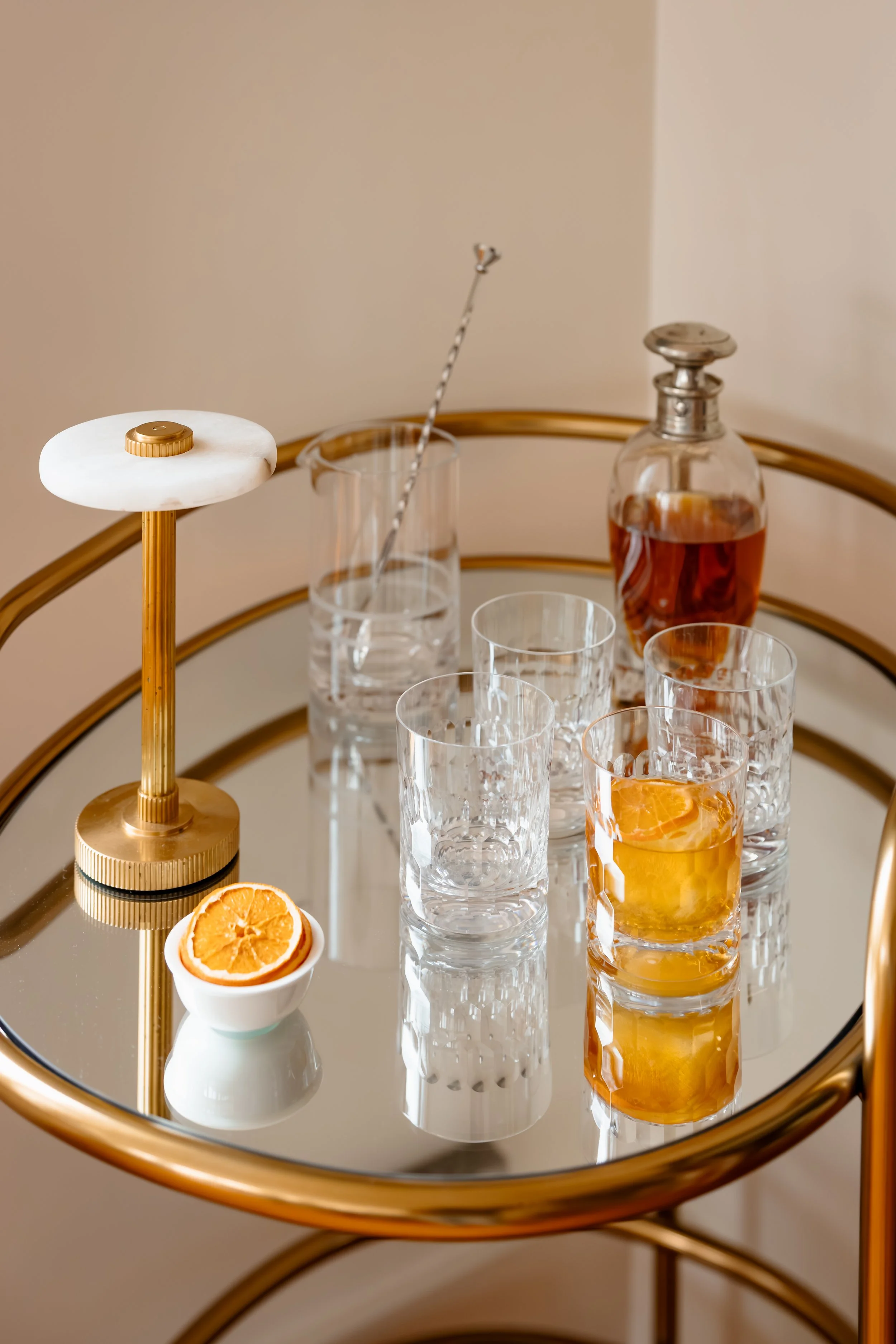 Brass bar cart styled with glassware, decanter, and citrus garnish.