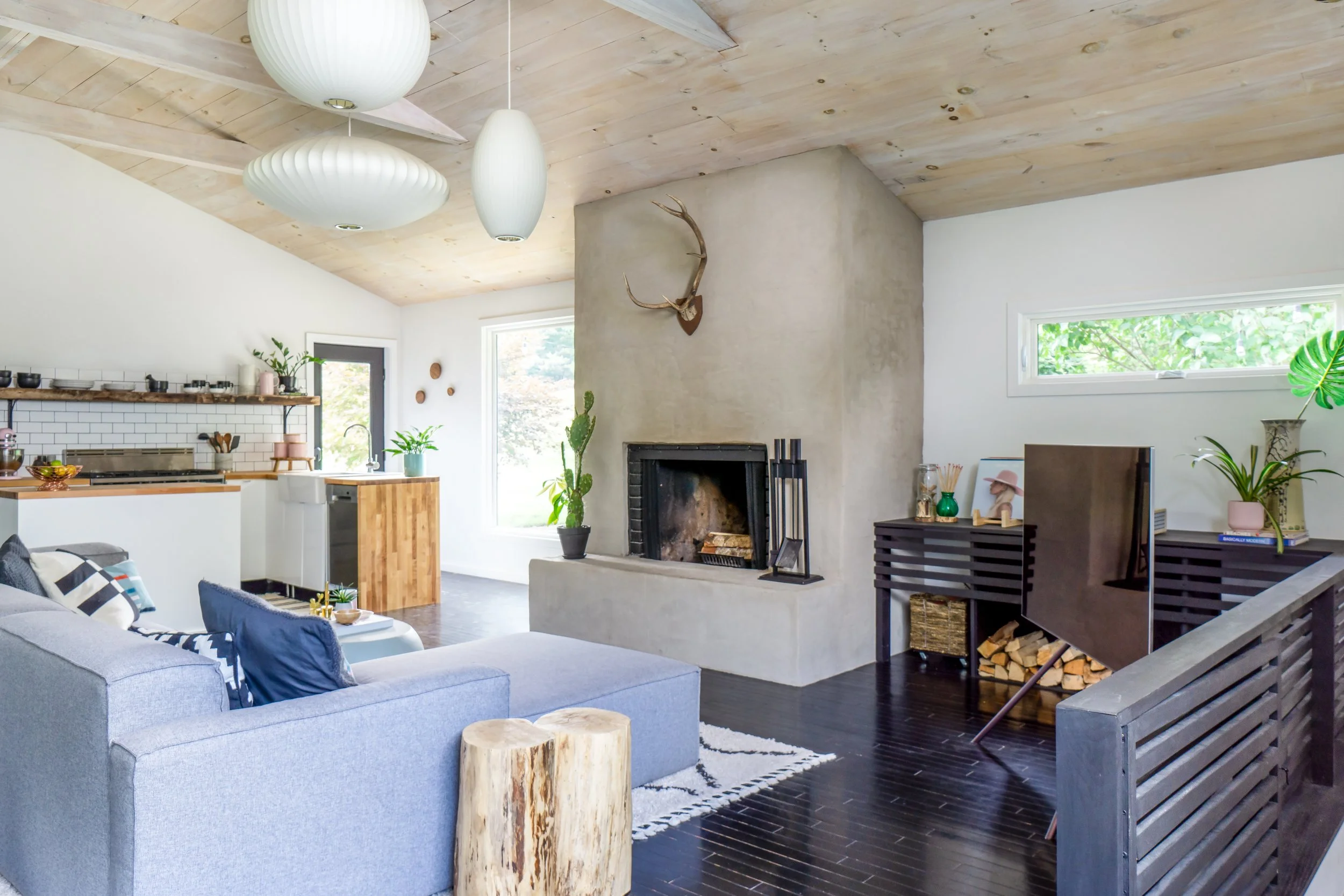 Living room with plaster fireplace, black floors, wood ceiling beams, and neutral furnishings.