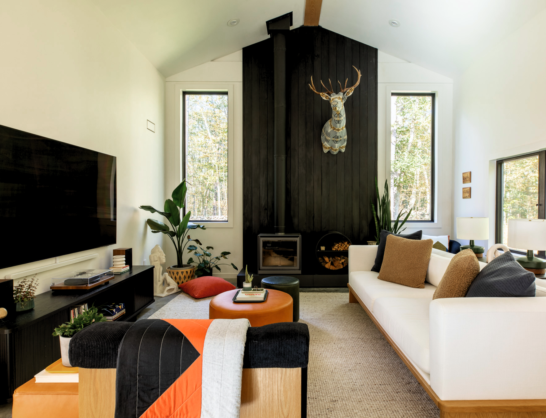 Living room with black paneled fireplace wall, mounted deer sculpture, and modern furnishings.