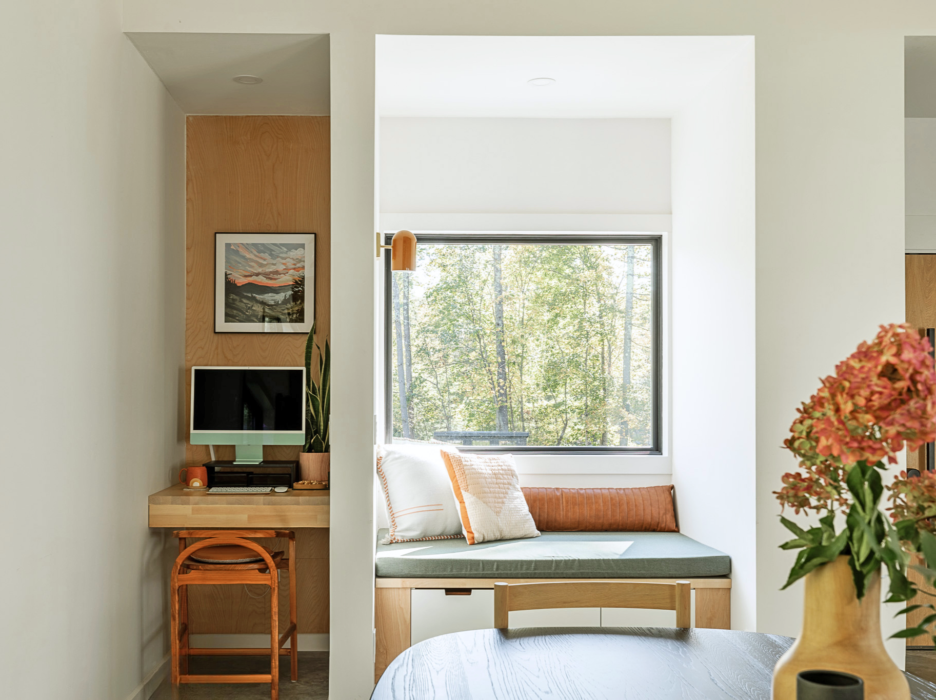 Compact home office with built-in desk and window bench seating.