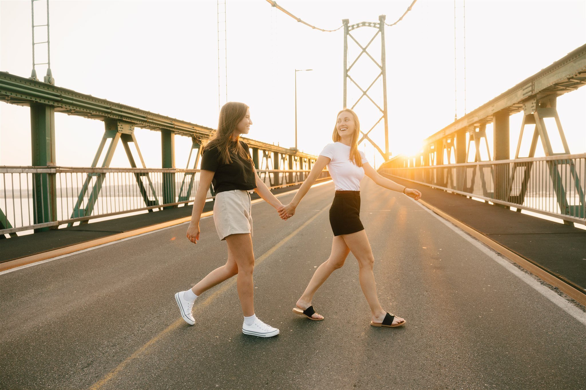 Deux femmes marchant main dans la main sur un pont à Québec au coucher du soleil, photographiées par Vincent Labonté