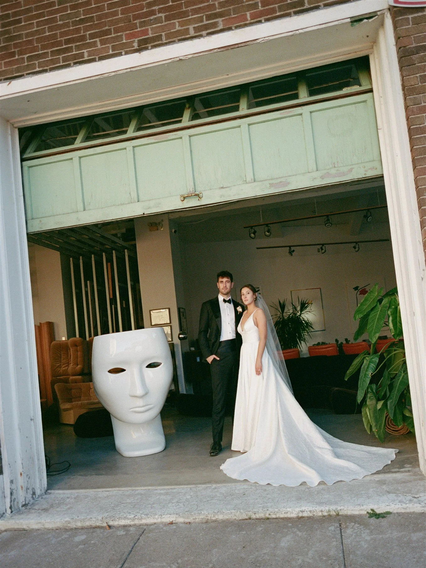Jeune couple habillée pour un mariage, dans un espace intérieur avec plantes vertes et décoration moderne.