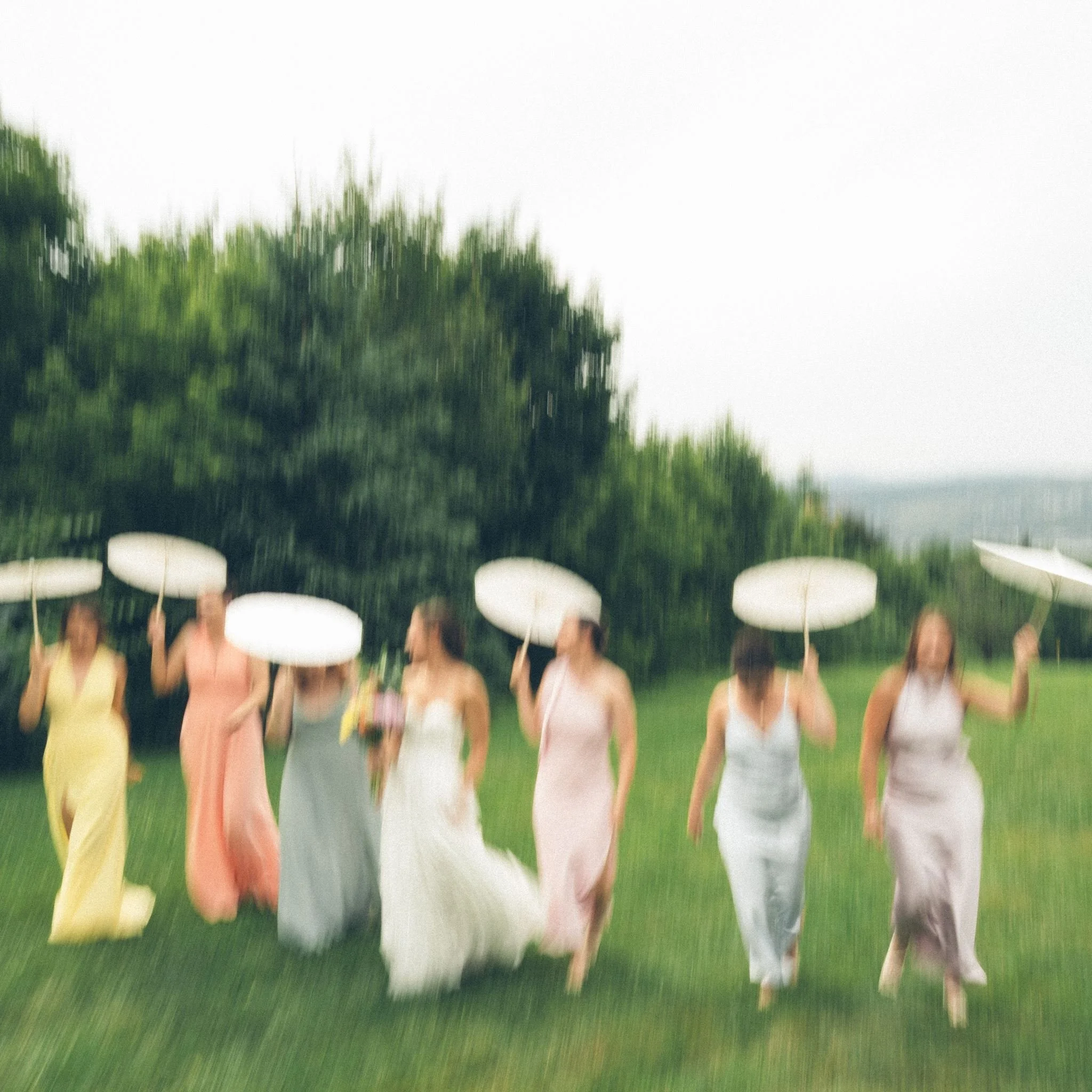 Groupe de personnes participant à une cérémonie de mariage en extérieur, portant des parasols blancs.