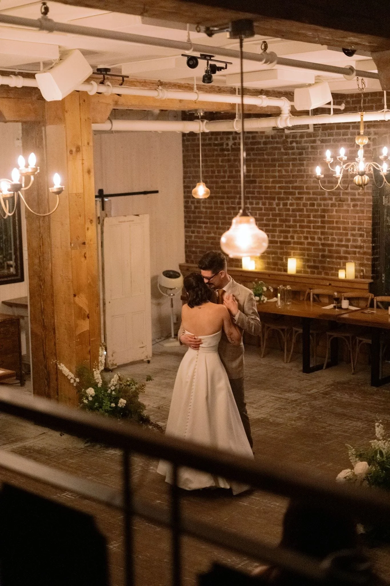 Un couple danse lors d'une cérémonie de mariage dans une salle décorée avec des chandelles et un éclairage chaleureux.