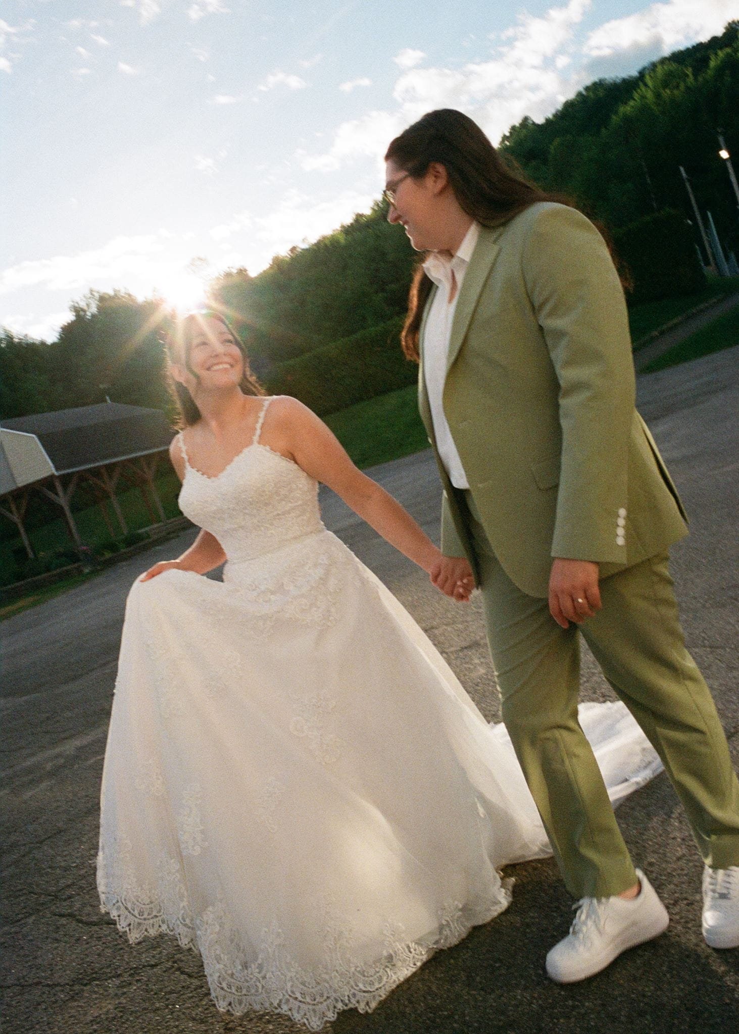 Deux femmes, dont une en robe de mariée et l'autre en costume kaki, se tiennent par la main dans un cadre extérieur lors d'une cérémonie