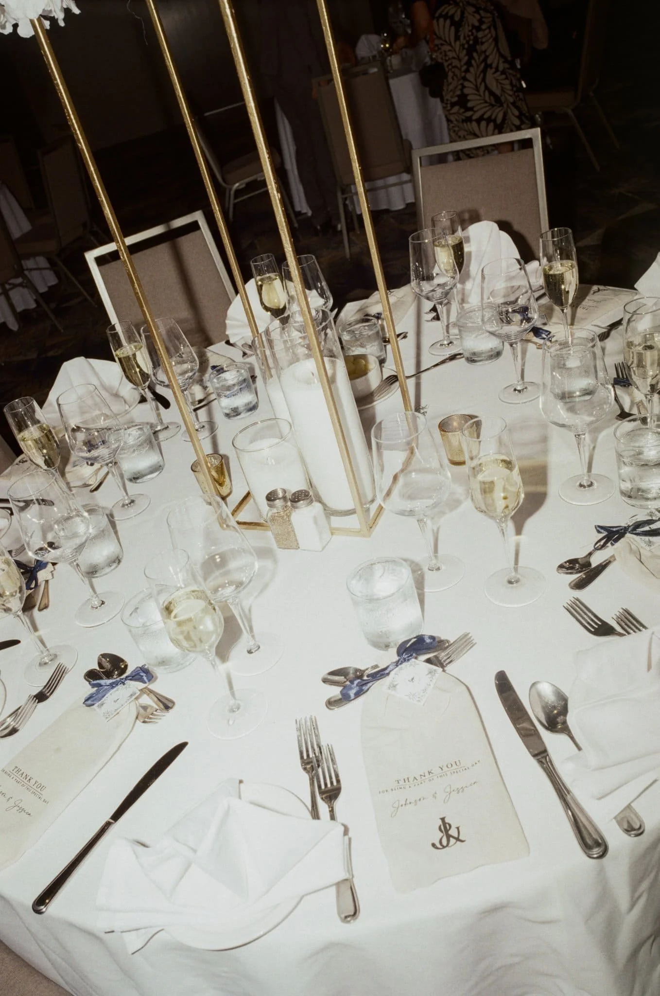 Table de banquet décorée avec élégance, comprenant verres à vin, assiettes, couverts et un centre de table doré et blanc, dans un cadre de restaurant ou d’événement formel, captée par un Photographe mariage Québec à Montréal.