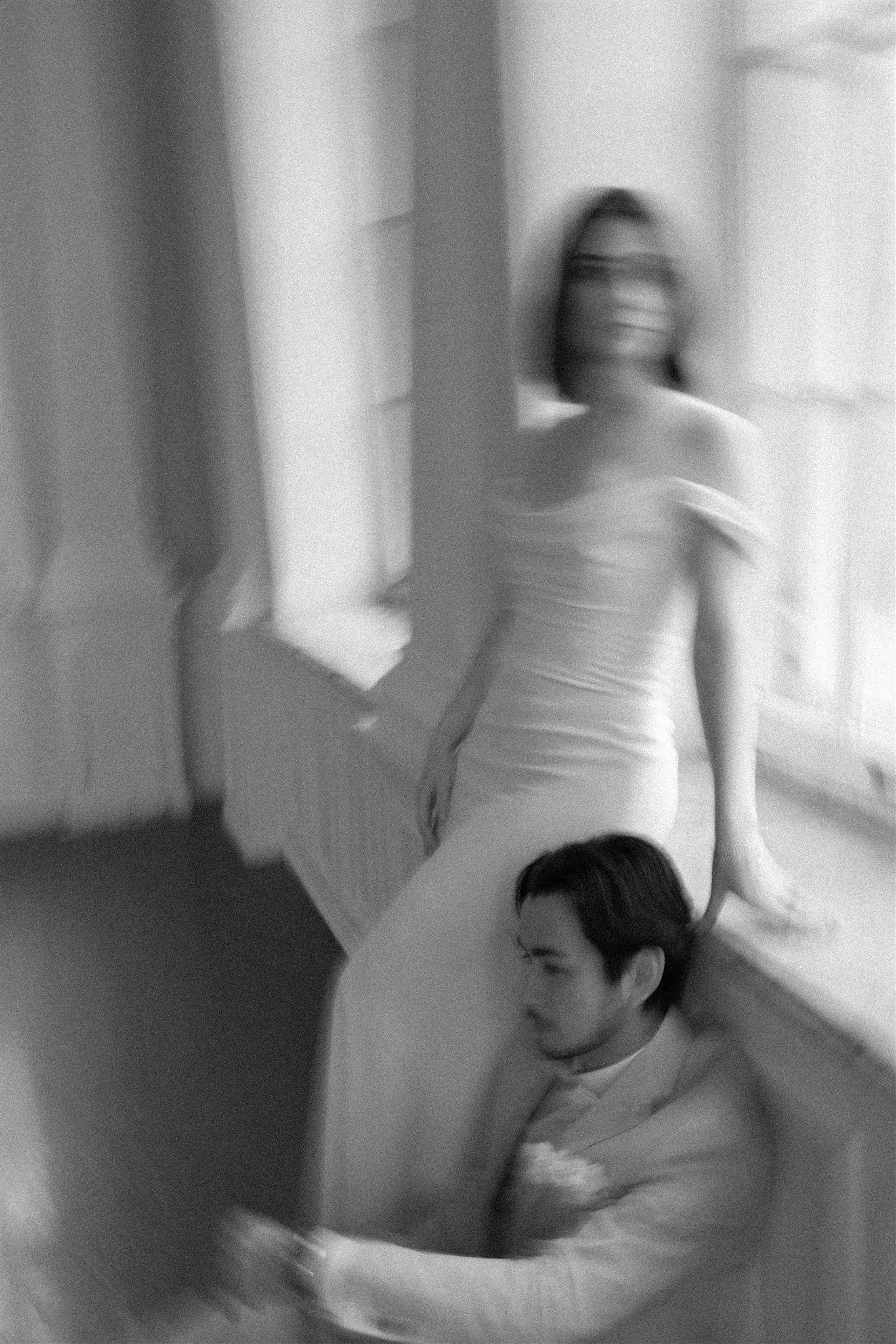 Une image en noir et blanc de deux jeunes enfants, dont un avec des lunettes, qui joue ou interagit avec un adulte dans une pièce intérieure.