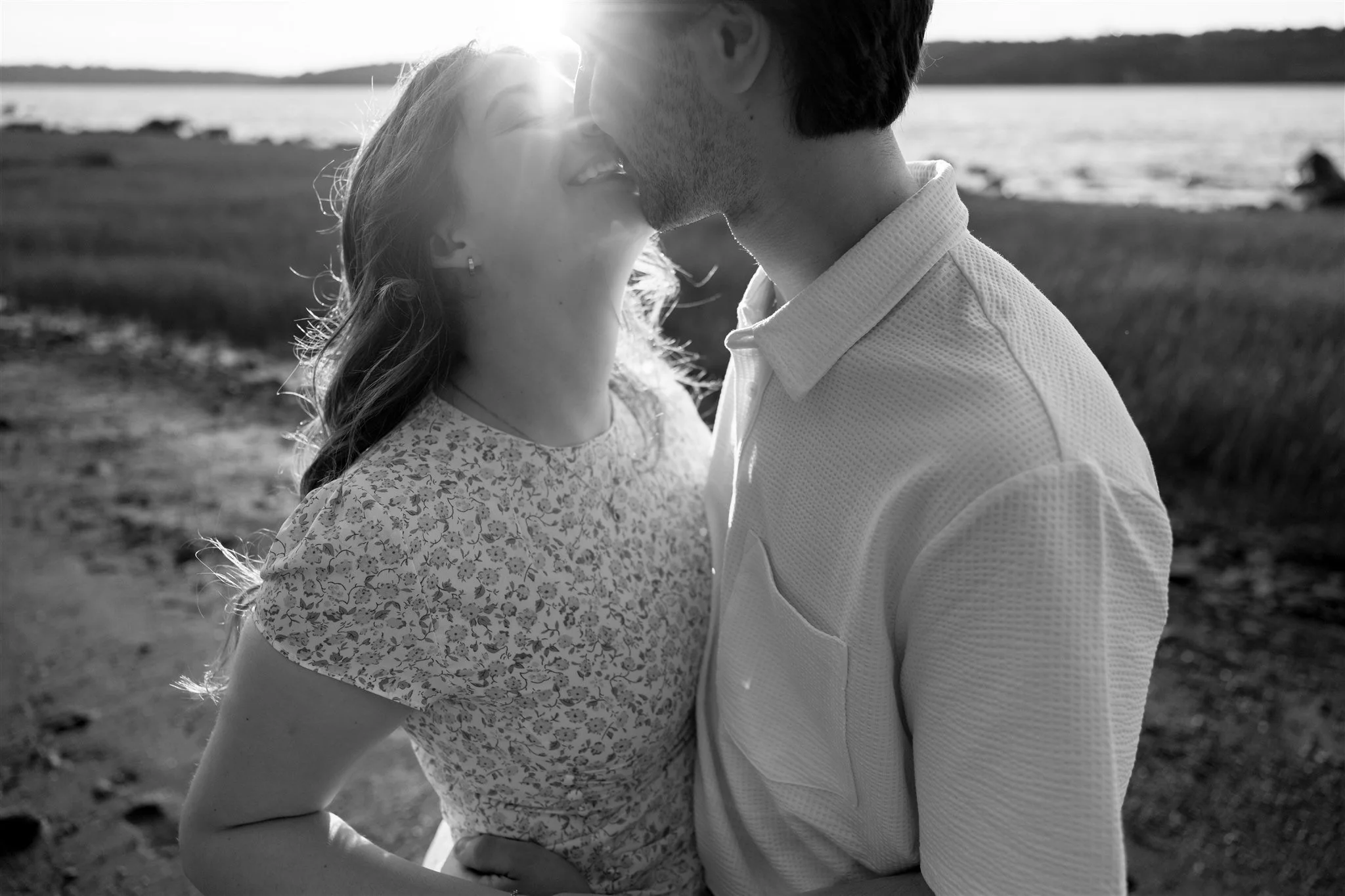 Couple s’embrassant au bord du fleuve Saint Laurent au coucher du soleil, en noir et blanc, capté par un Photographe mariage Québec à Lévis.