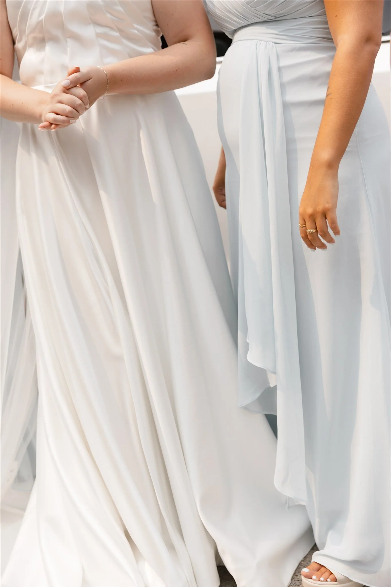 Deux femmes en robes blanches élégantes, debout côte à côte, lors d'une cérémonie ou d'une occasion spéciale.