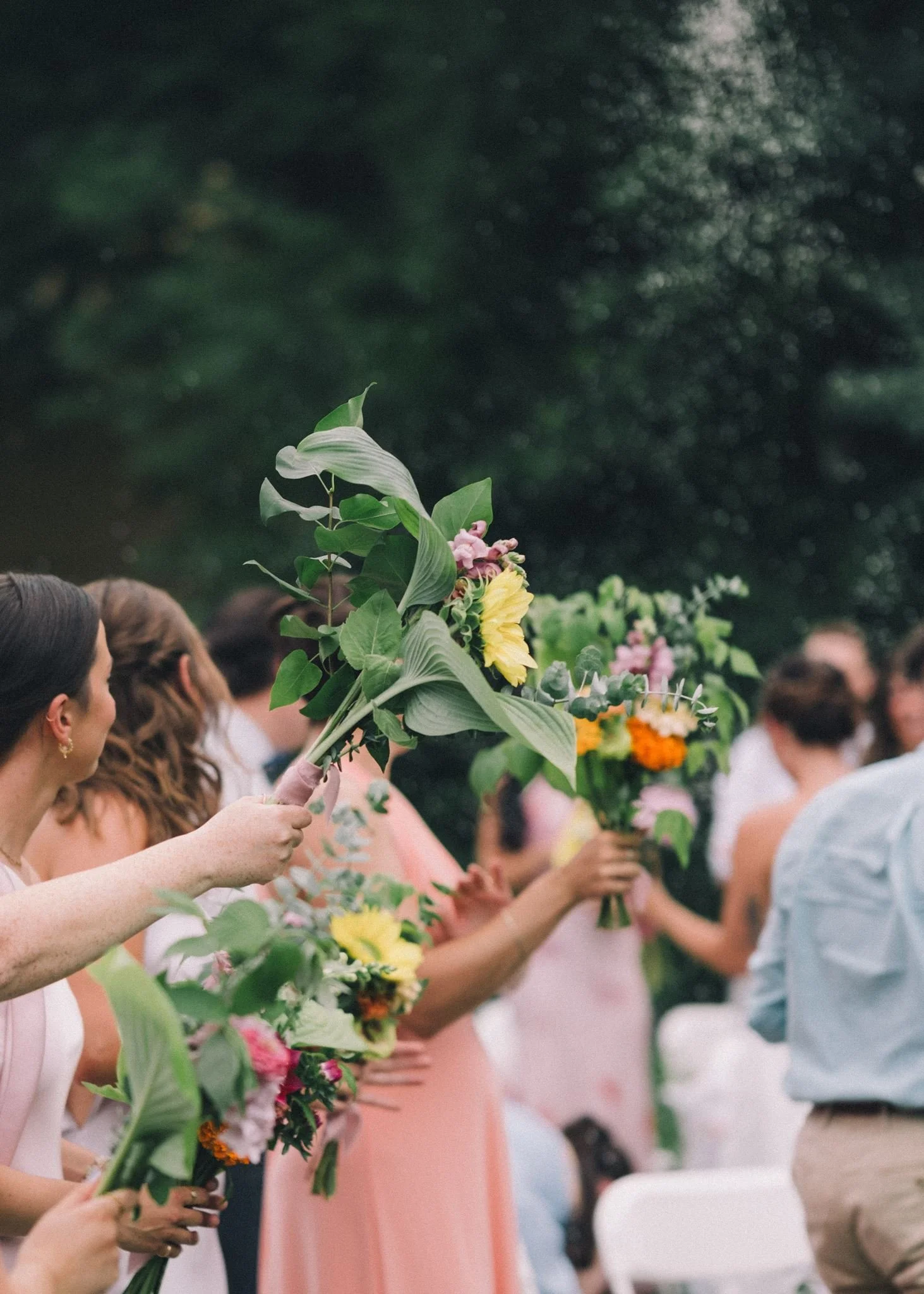 Groupe de personnes tenant des bouquets de fleurs lors d'une cérémonie en plein air.