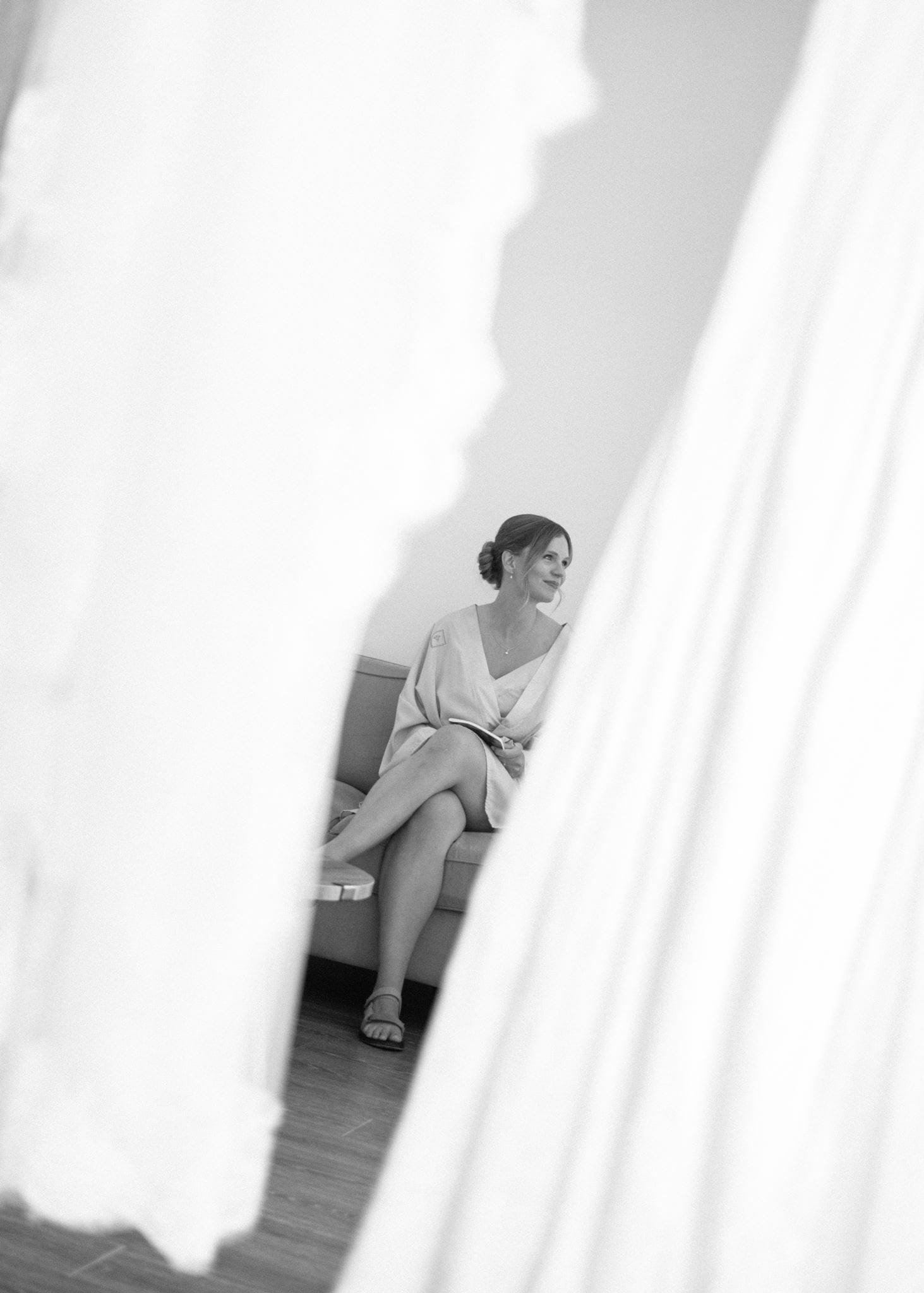 Une femme assise sur un canapé, vue partielle avec un drap blanc flou en premier plan.