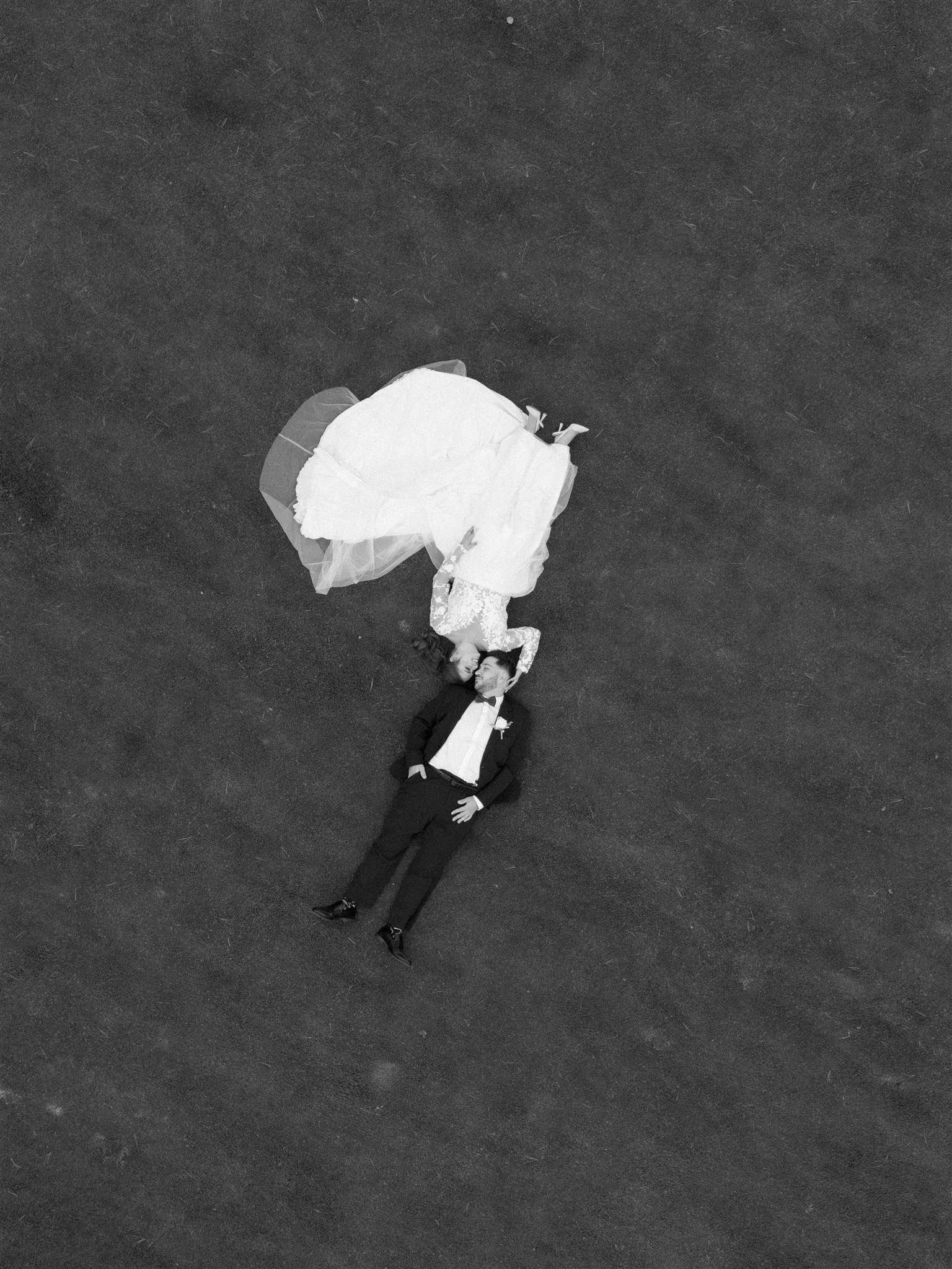 Couple en vêtements de mariage allongé au sol, vu en plongée, capté par un Photographe mariage Québec.