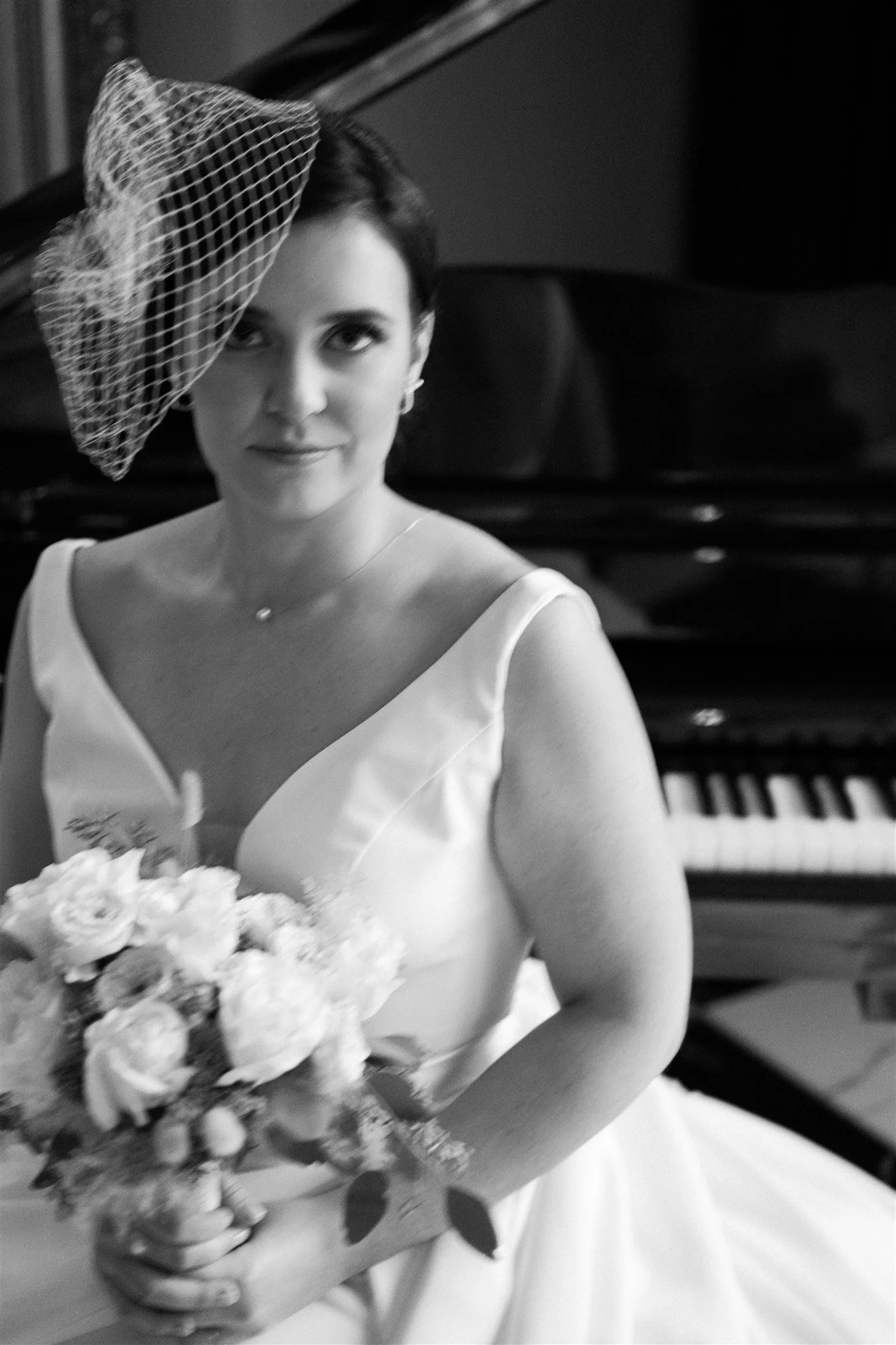 Femme habillée en robe de mariée tenant un bouquet de fleurs, probablement lors d'un mariage, en noir et blanc.