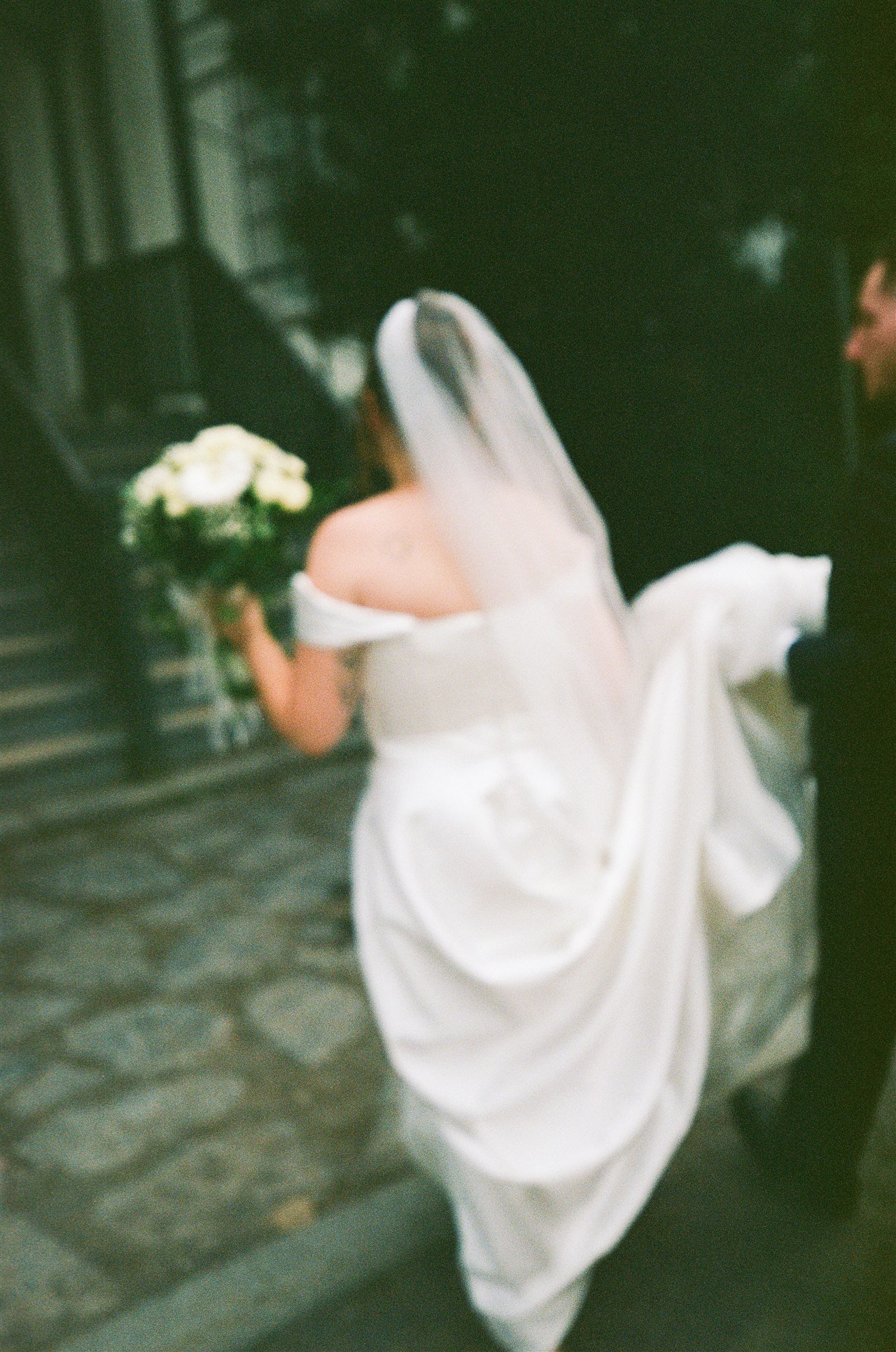 Une personne en robe blanche tenant un bouquet de fleurs, assise dans une voiture.
