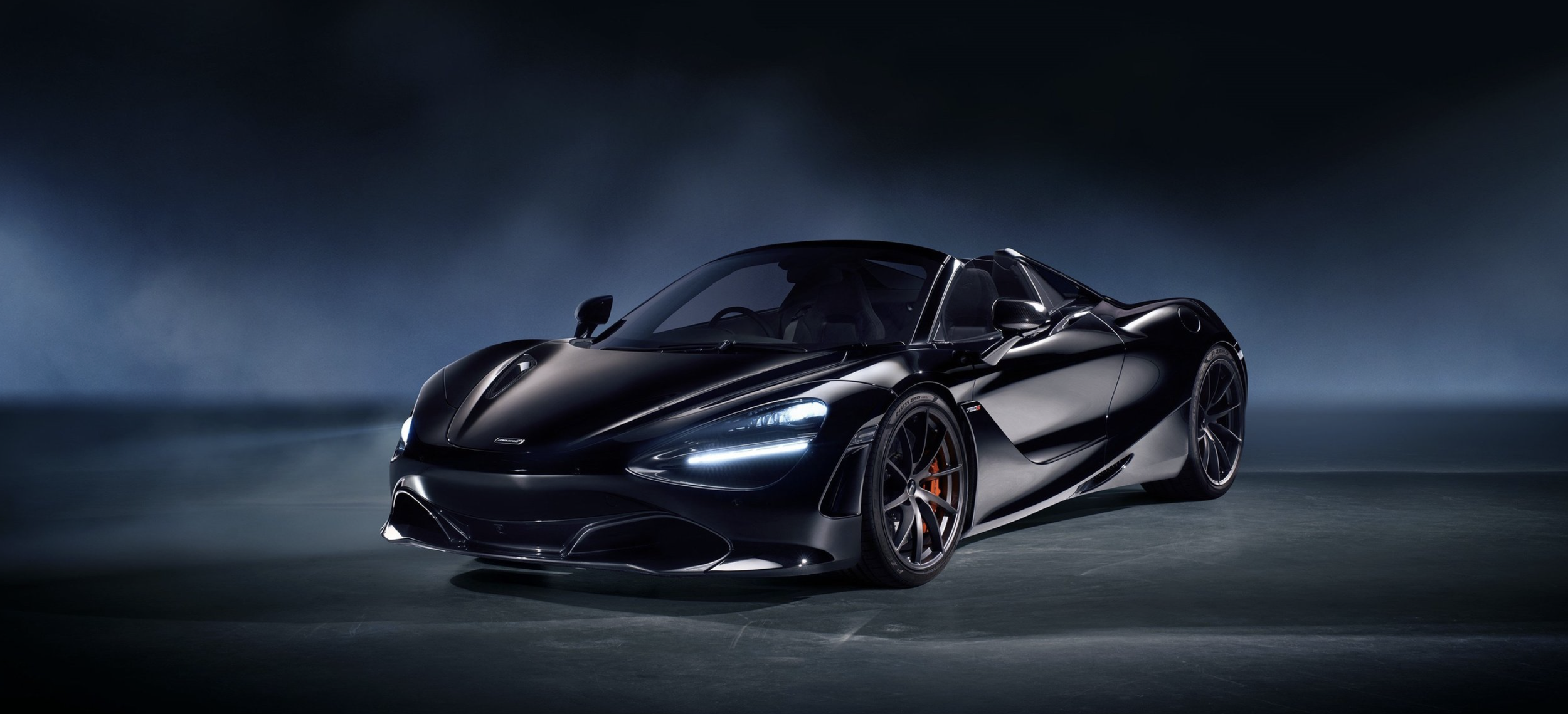 A sleek, black sports car under dramatic lighting on a dark background.