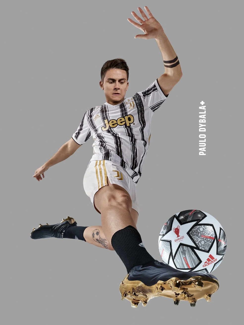 Soccer player Paulo Dybala in Juventus uniform kicking a soccer ball, with a gray background.