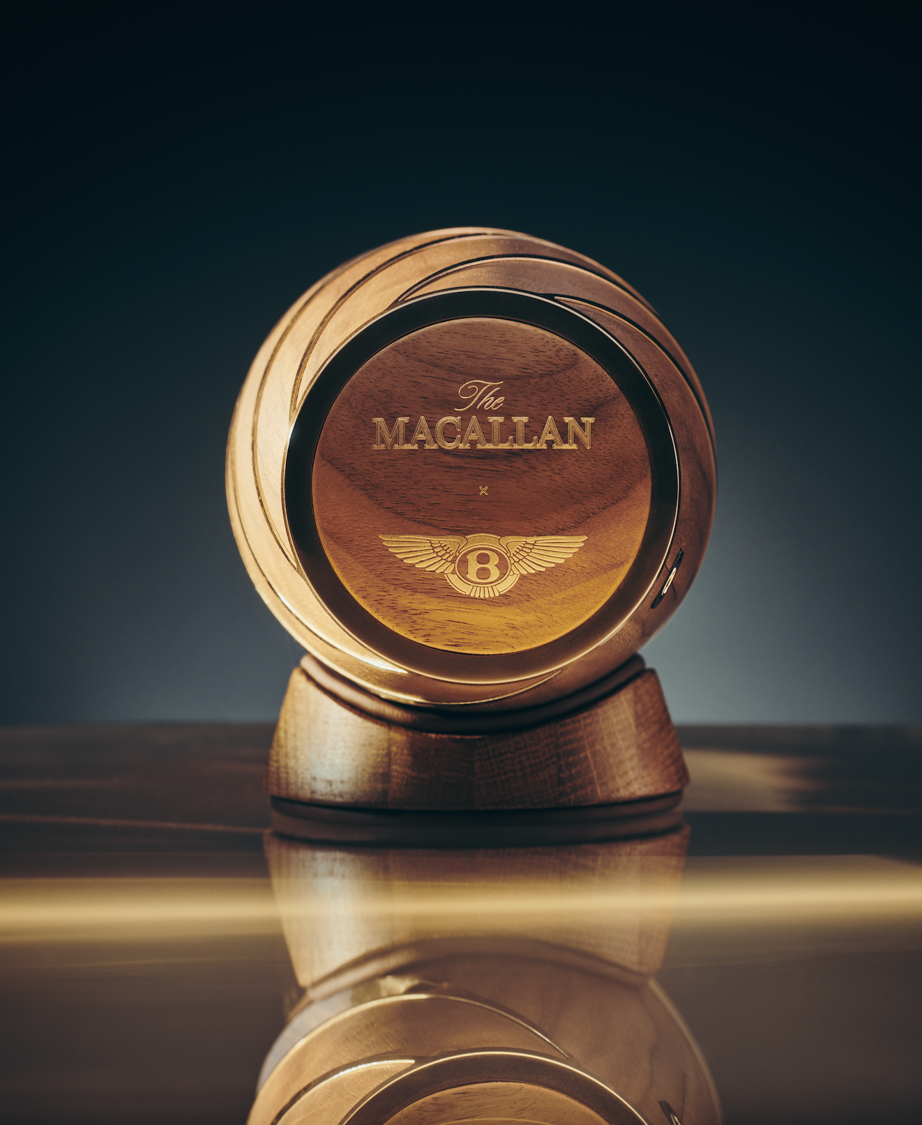 A round, wooden desktop clock with the logo and name of Bentley Motors, with reflection visible on the table surface.