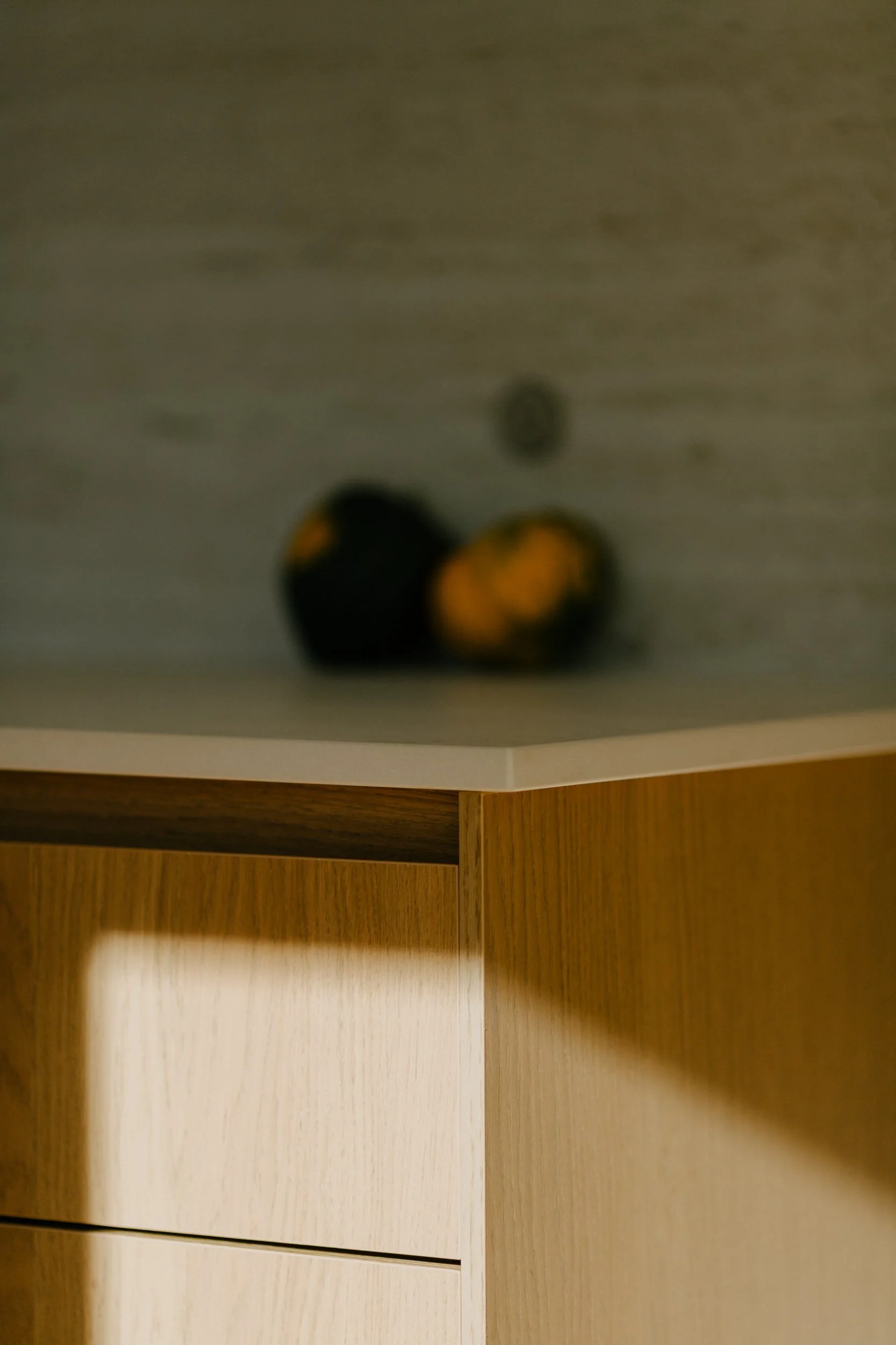 Blurred view of two black and yellow objects and one gray ball on a wooden surface.