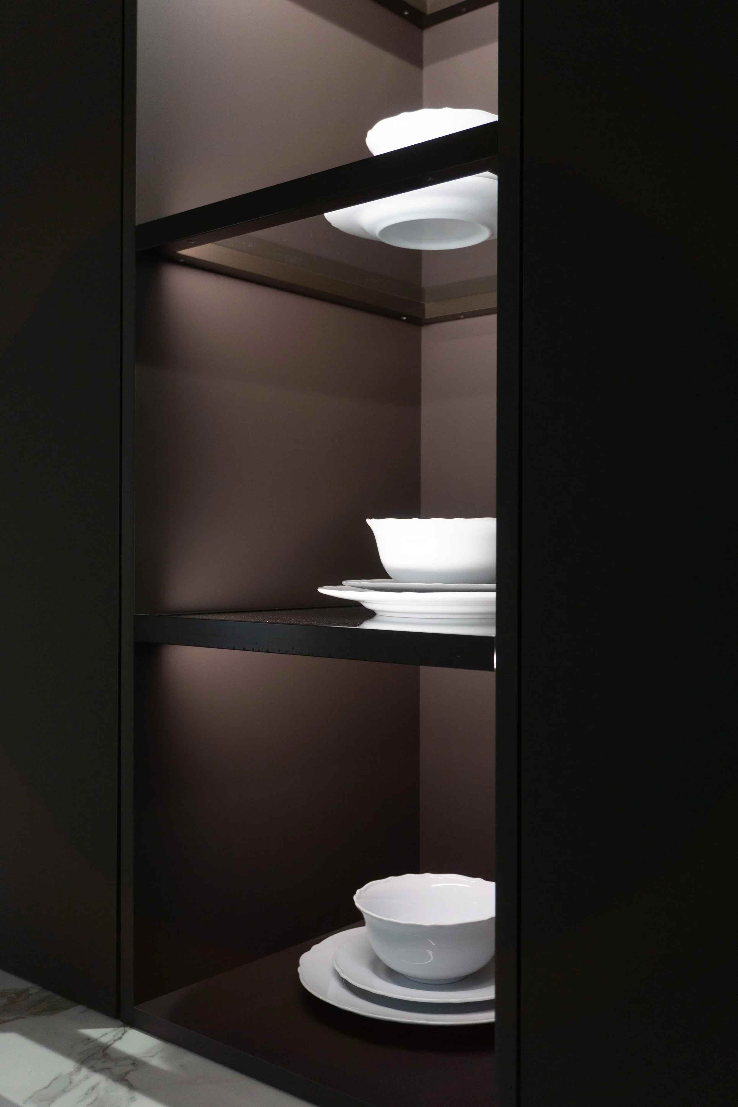 Open black cabinet with white dishes on shelves