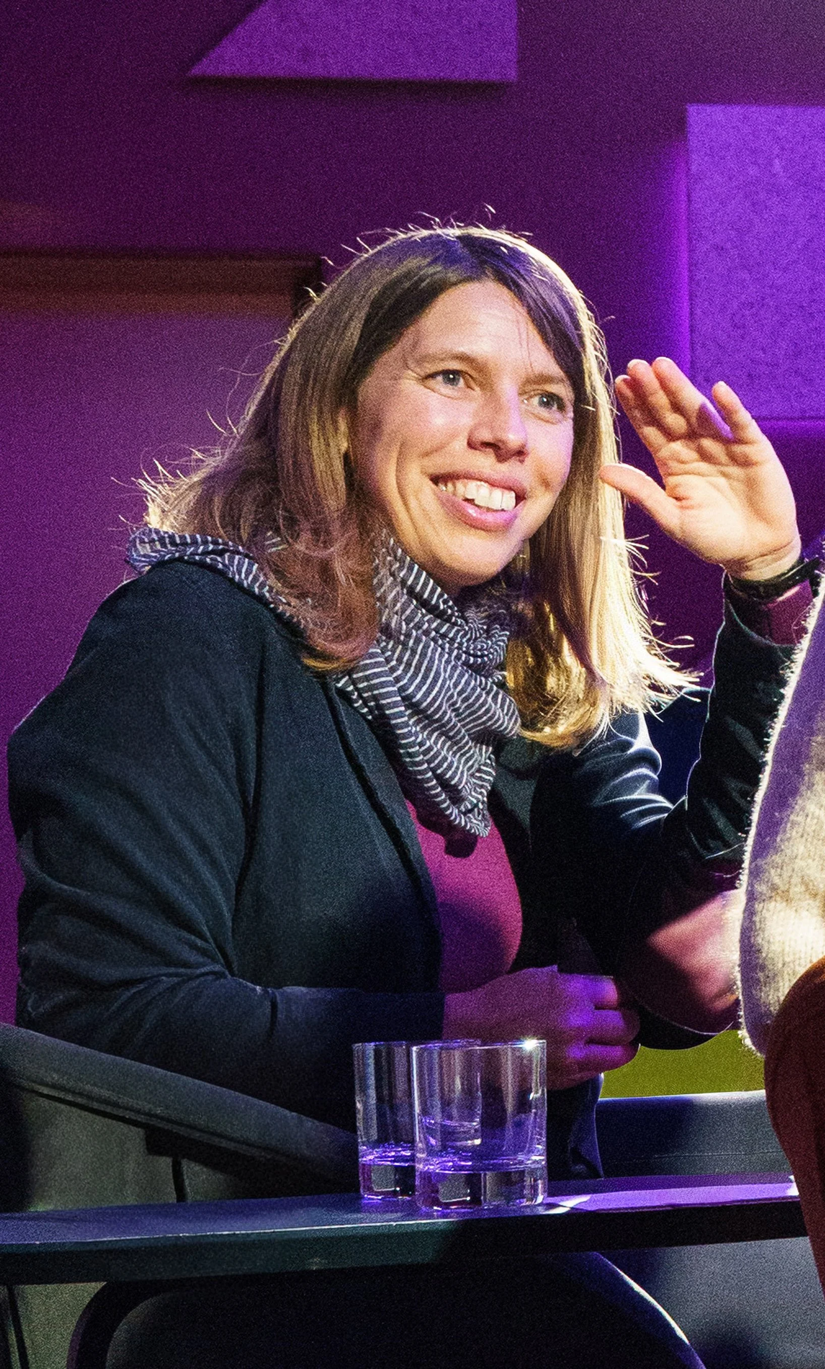 Bernadette Klausberger sitzt in einem Konferenzsessel und spricht angeregt mit einer anderen Person