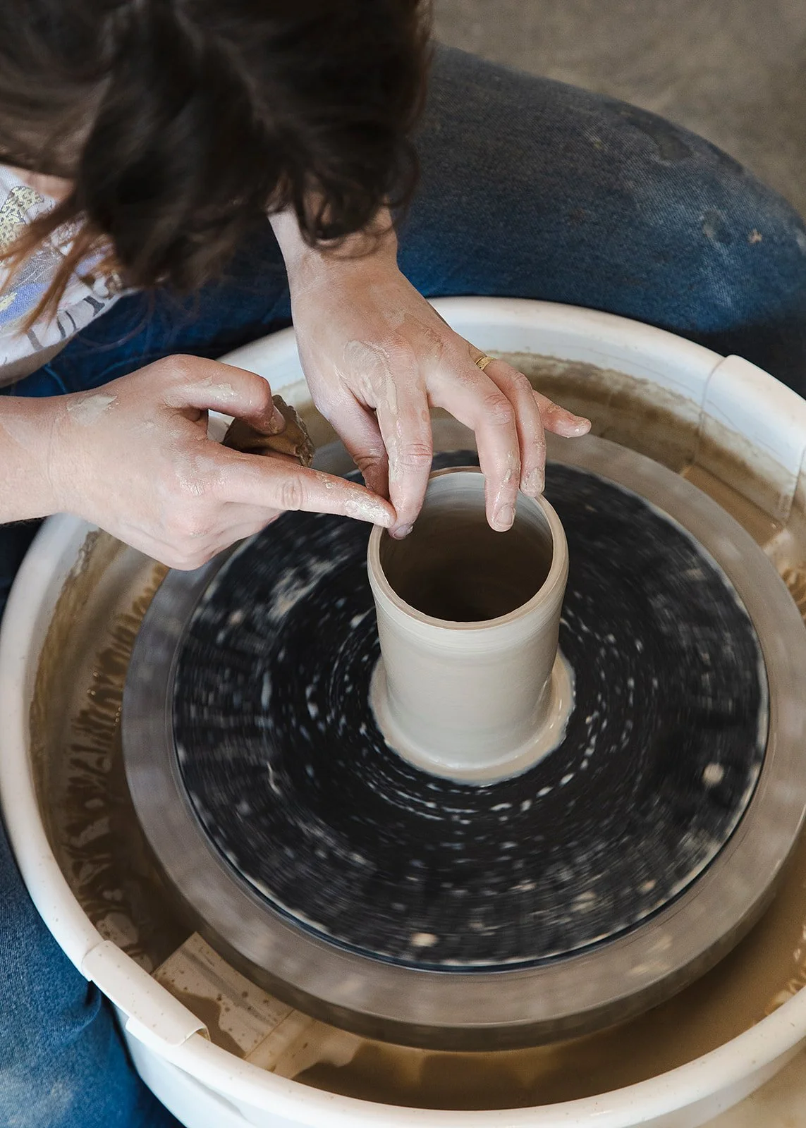 Overhead view of hands shaping a clay pot on a pottery wheel at Still Life Ceramics Studio RVA.
