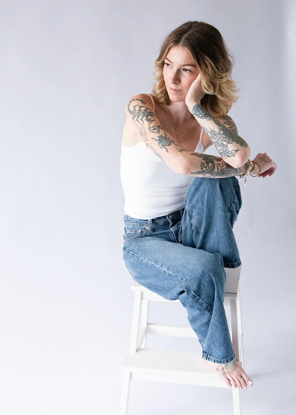 Creative branding photo of a woman sitting on a white stool in a seamless studio, taken by Fairy Bread Photography in Richmond, VA.