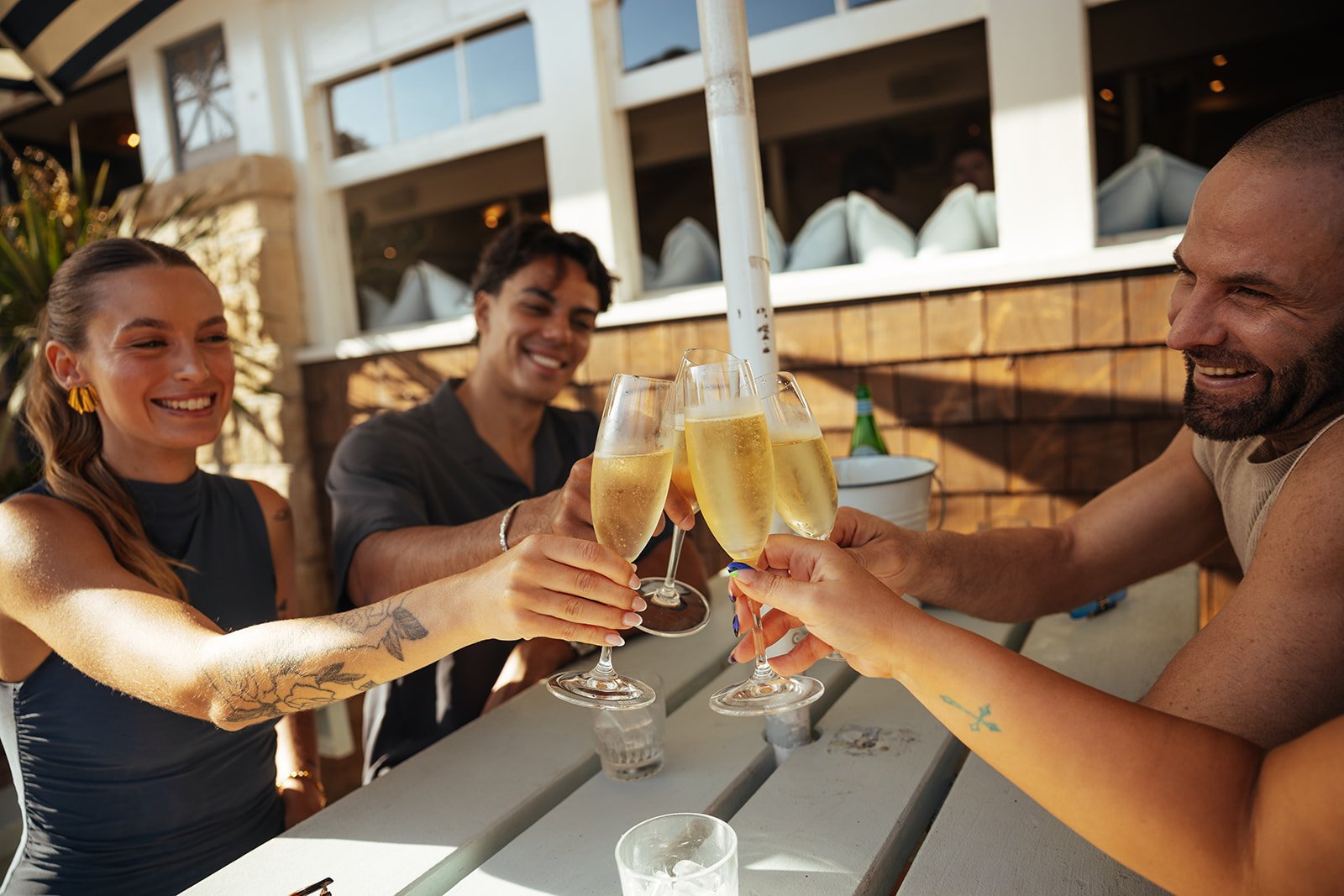 Four friends clinking glasses of champagne at an outdoor gathering, smiling and enjoying each other's company.