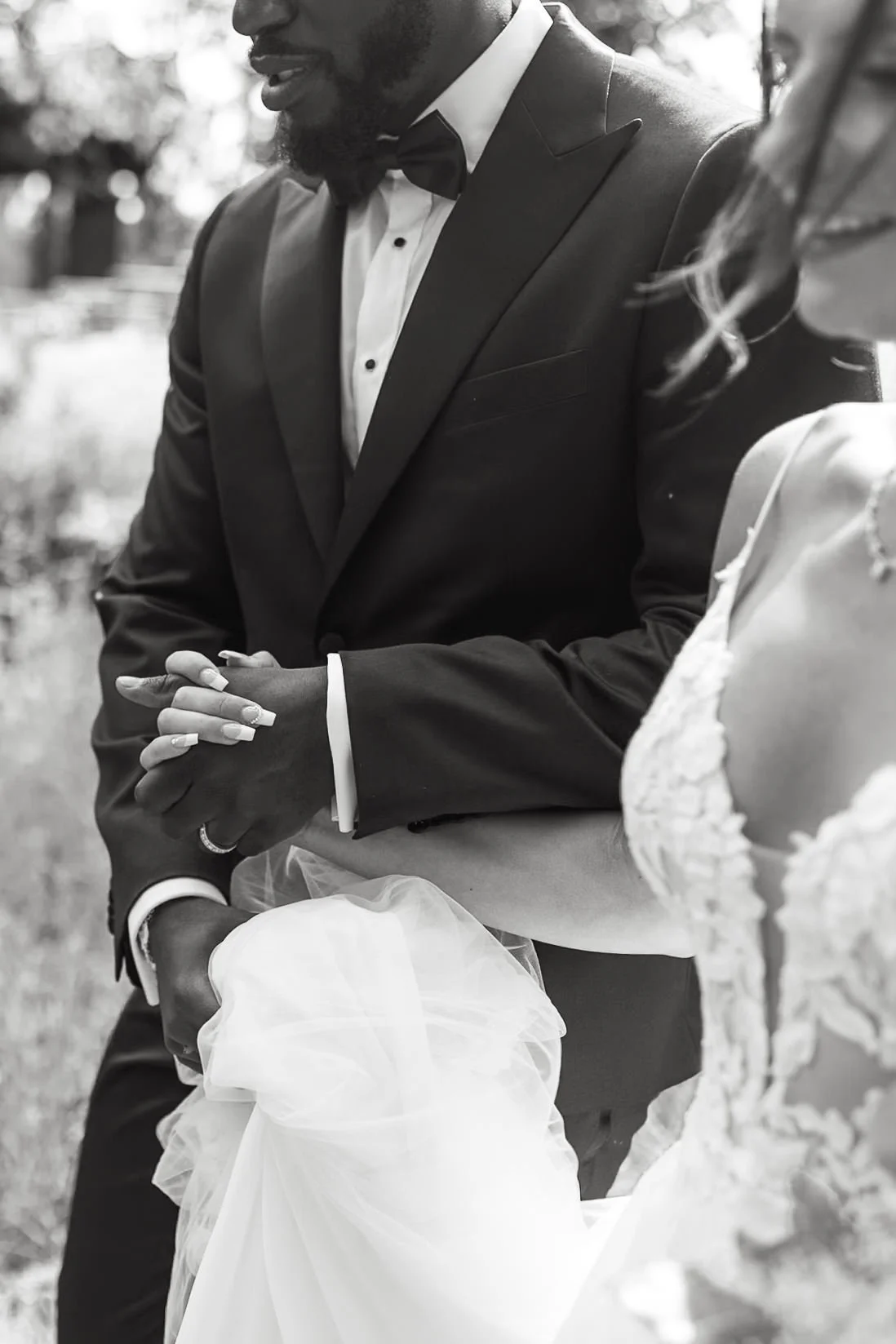 Candid black and white photo of bride and groom holding hands and laughing on their wedding day