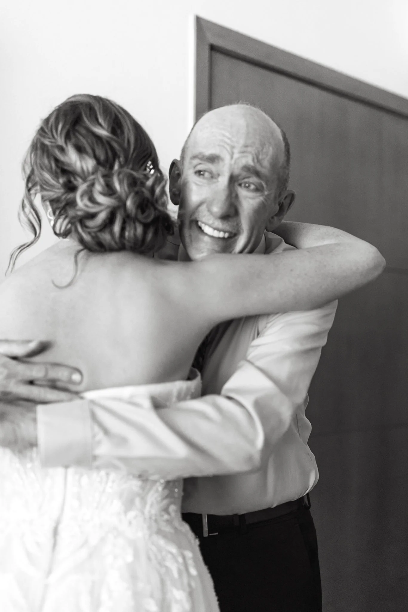 A woman in a wedding dress hugging her father in a light colored shirt, both smiling happily on her wedding day in Playa Del Carmen Mexico