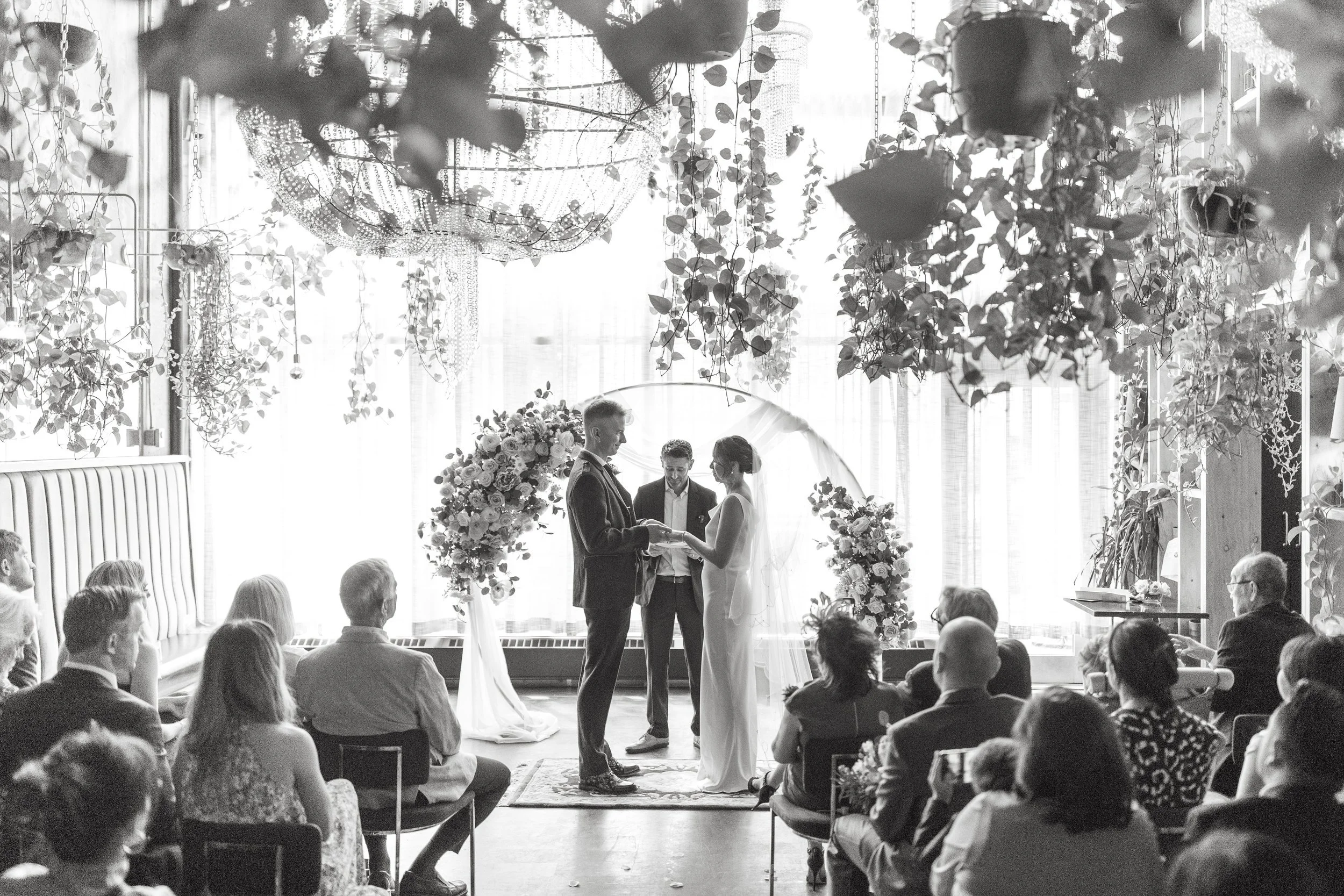 Black and white photo of bride and groom exchanging their vows during wedding ceremony at Orchard Restaurant in Downtown Calgary