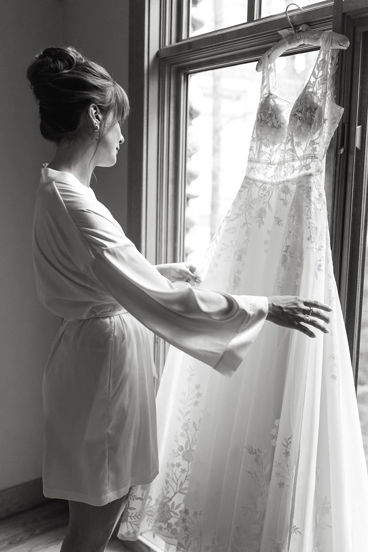 Bride looks at her vintage inspired lace wedding dress on the morning of her wedding in Canmore, Alberta