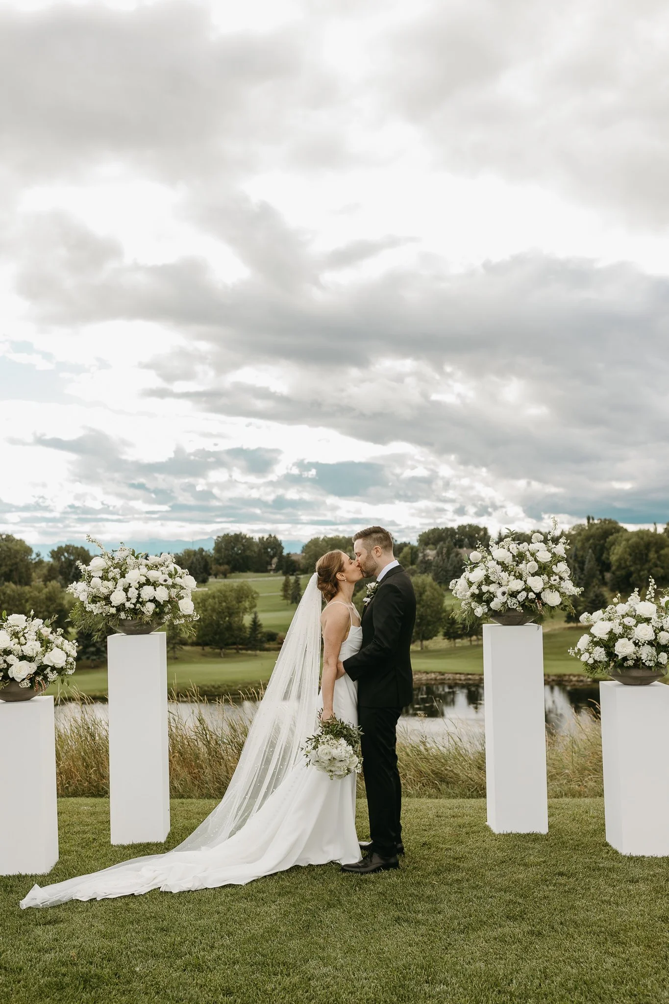 Bride and groom kiss during wedding ceremony with modern black and white decor at Bearspaw Golf Course in Calgary 