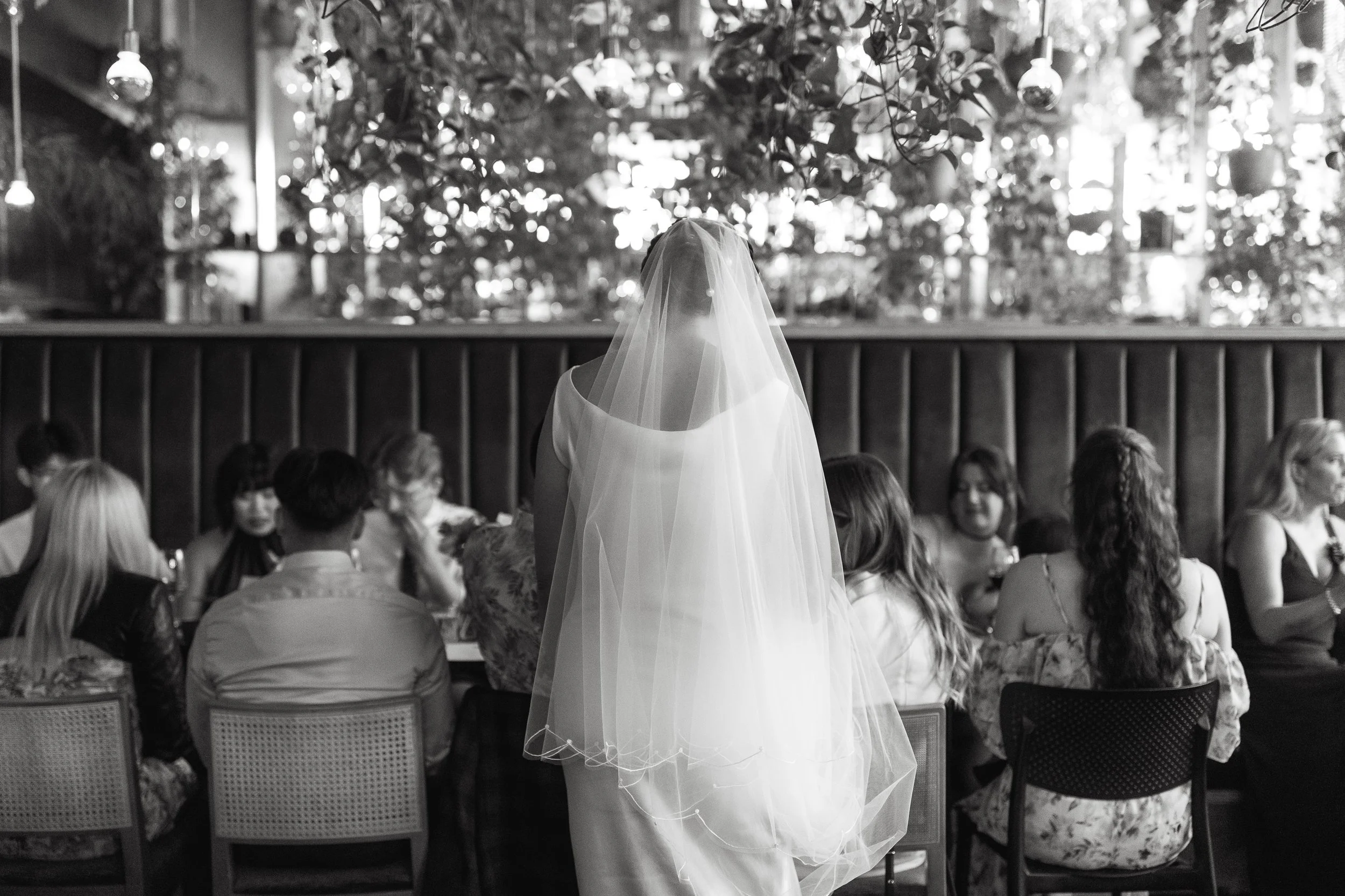 Bride with long veil greets her guests at wedding reception at Orchard Restaurant in Downtown Calgary 