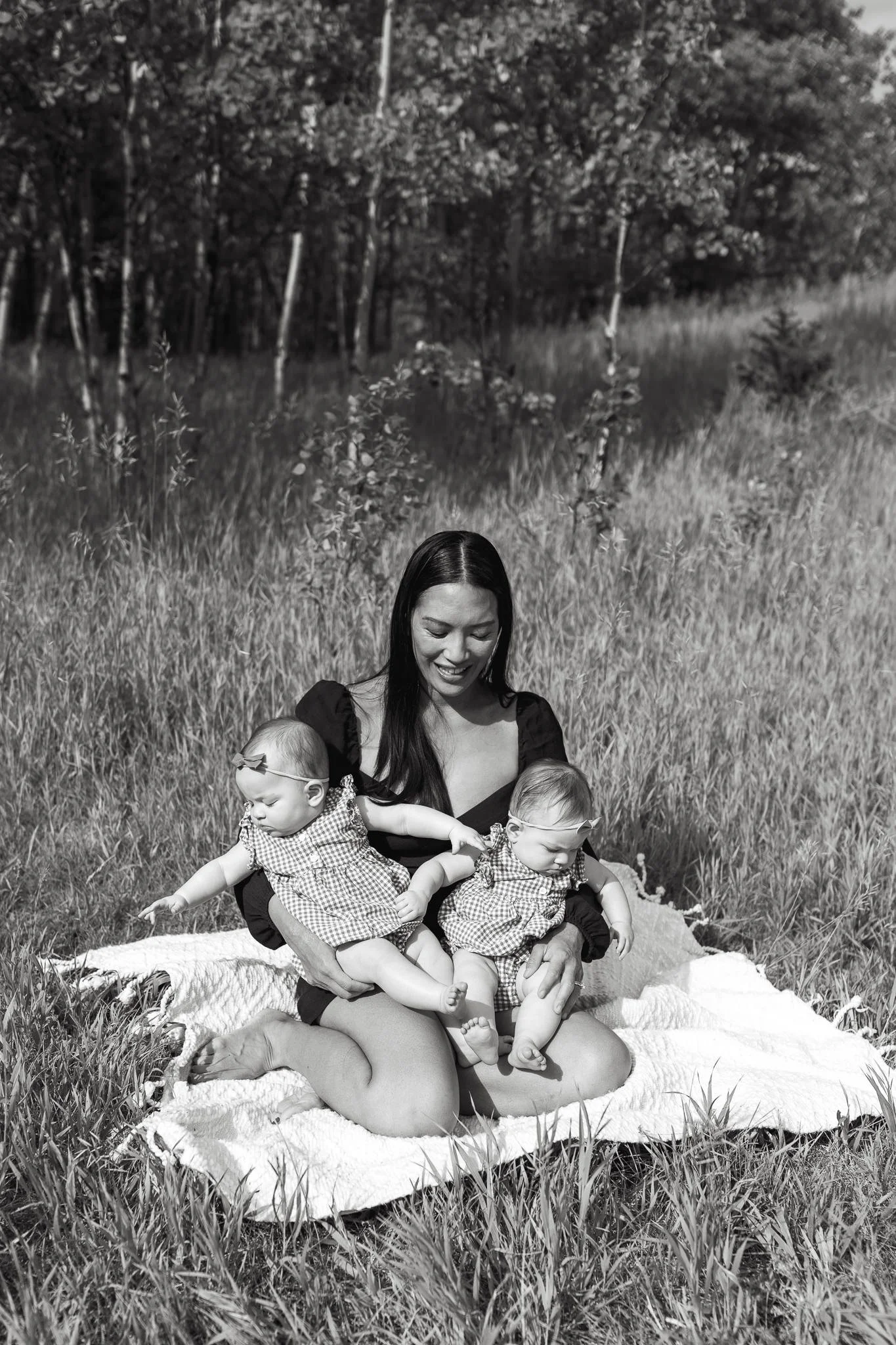 Black and white photo of mother holding her twin babies on a blanket in Calgary 