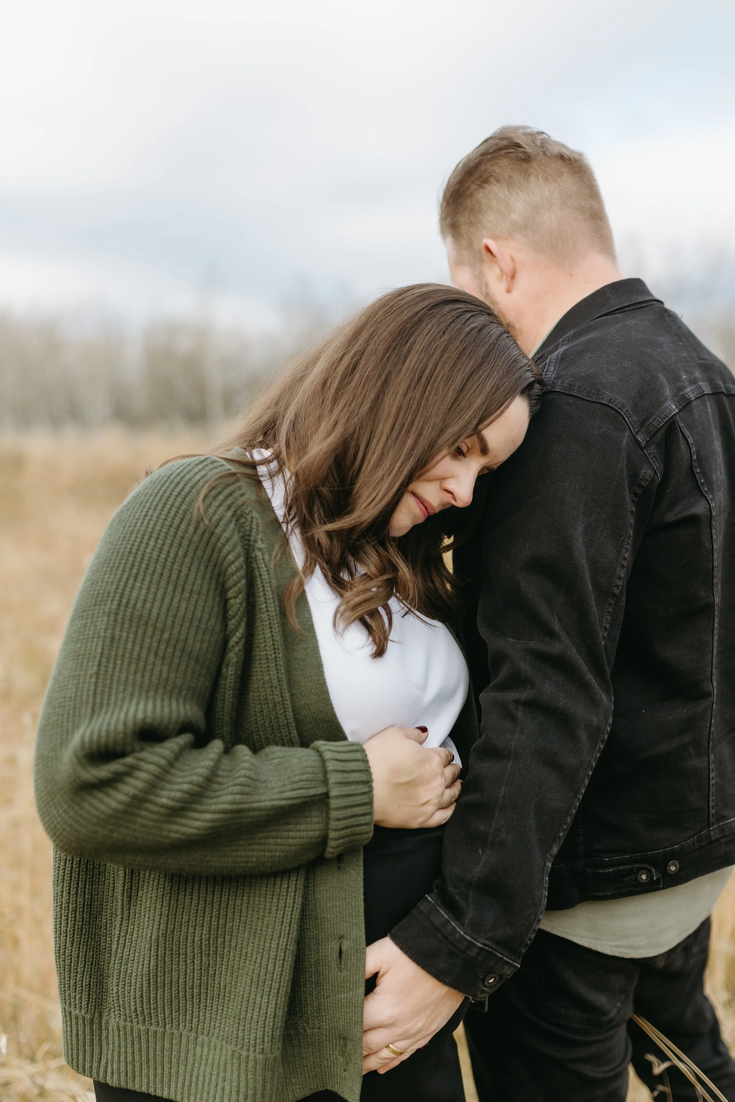 Pregnant women in green sweater shows off her belly at her fall maternity session in Calgary 