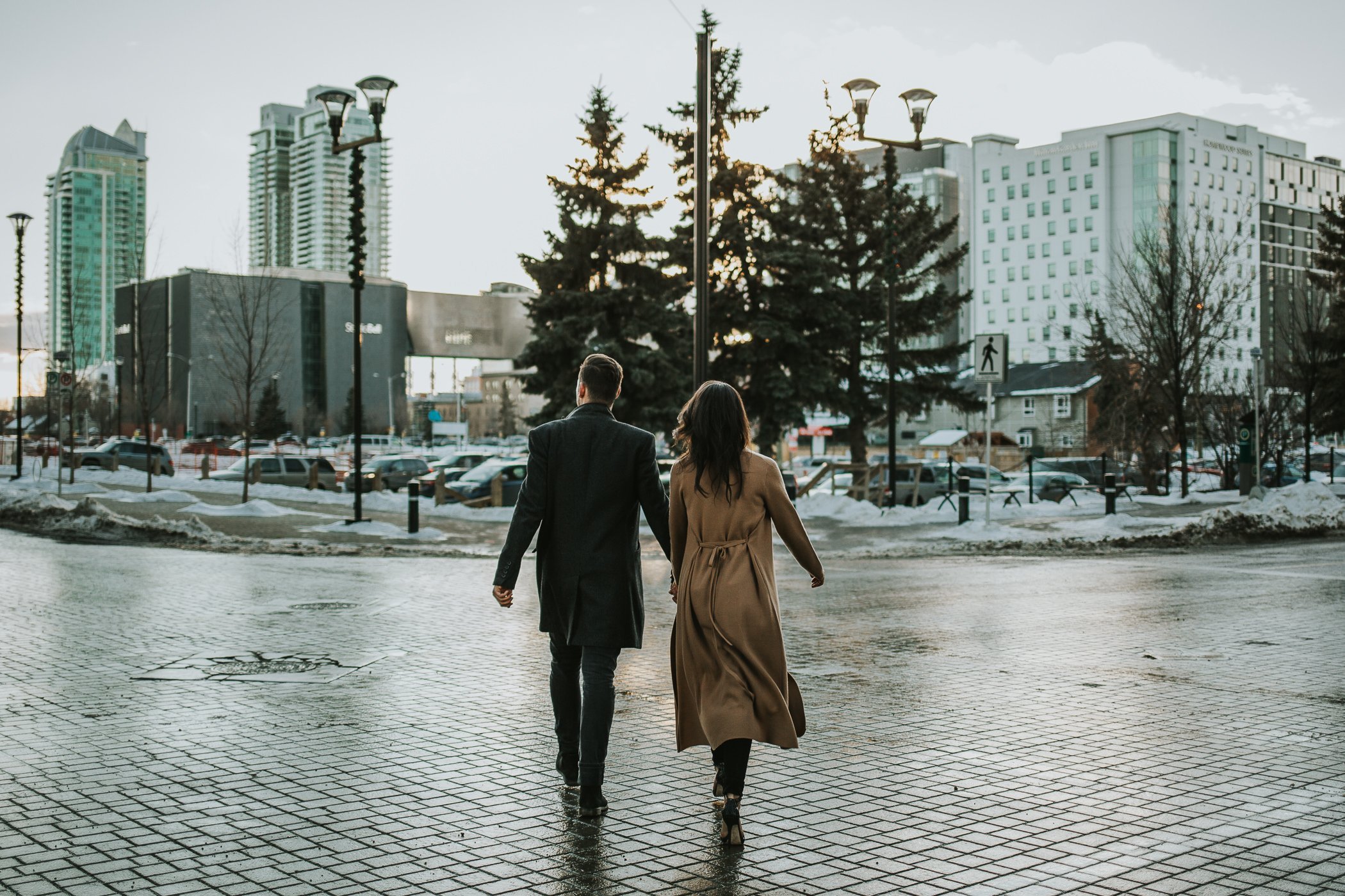Cole walking across the street in downtown Calgary at their engagement session