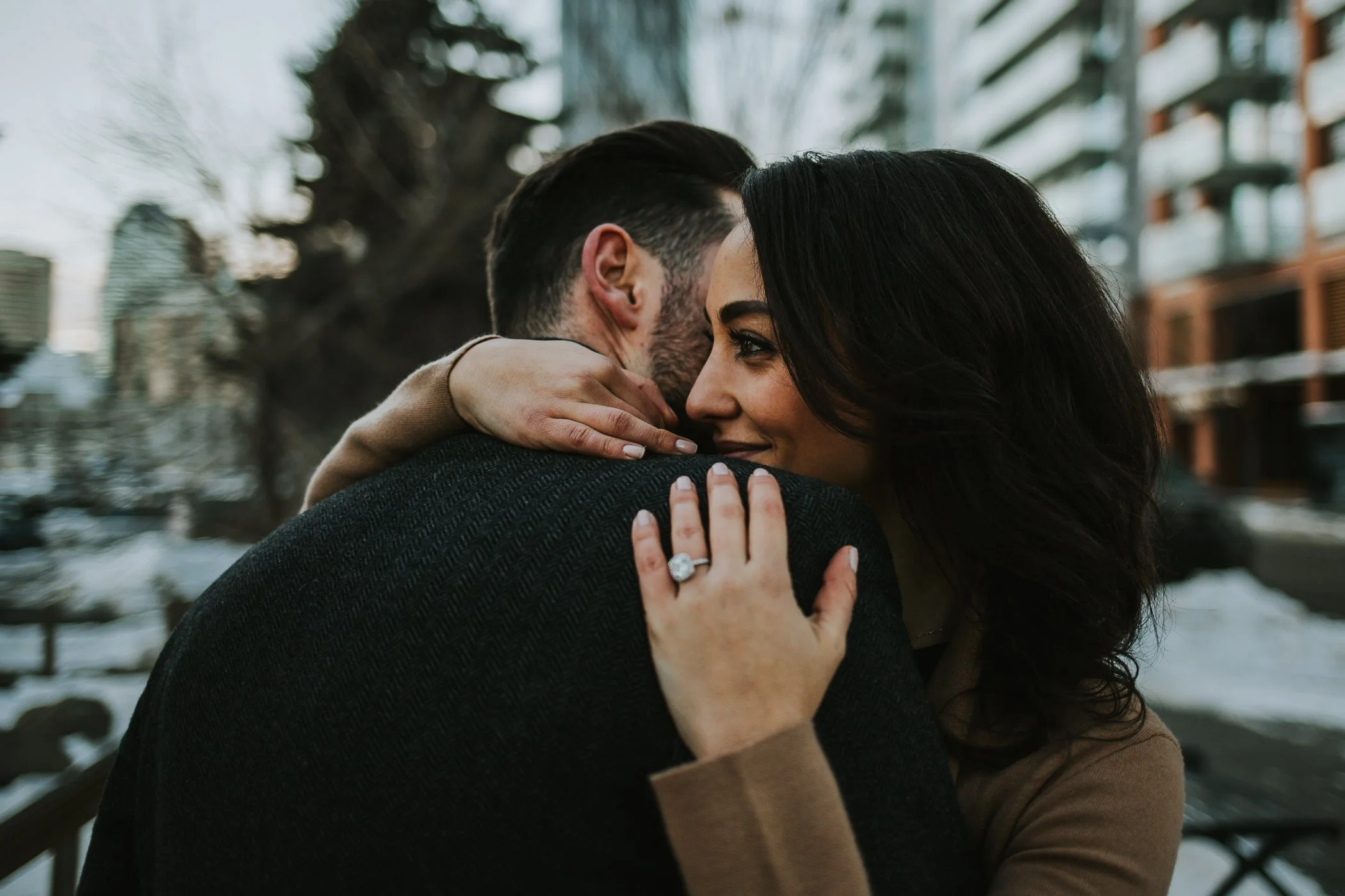 Couple hugging and showing off engagement ring