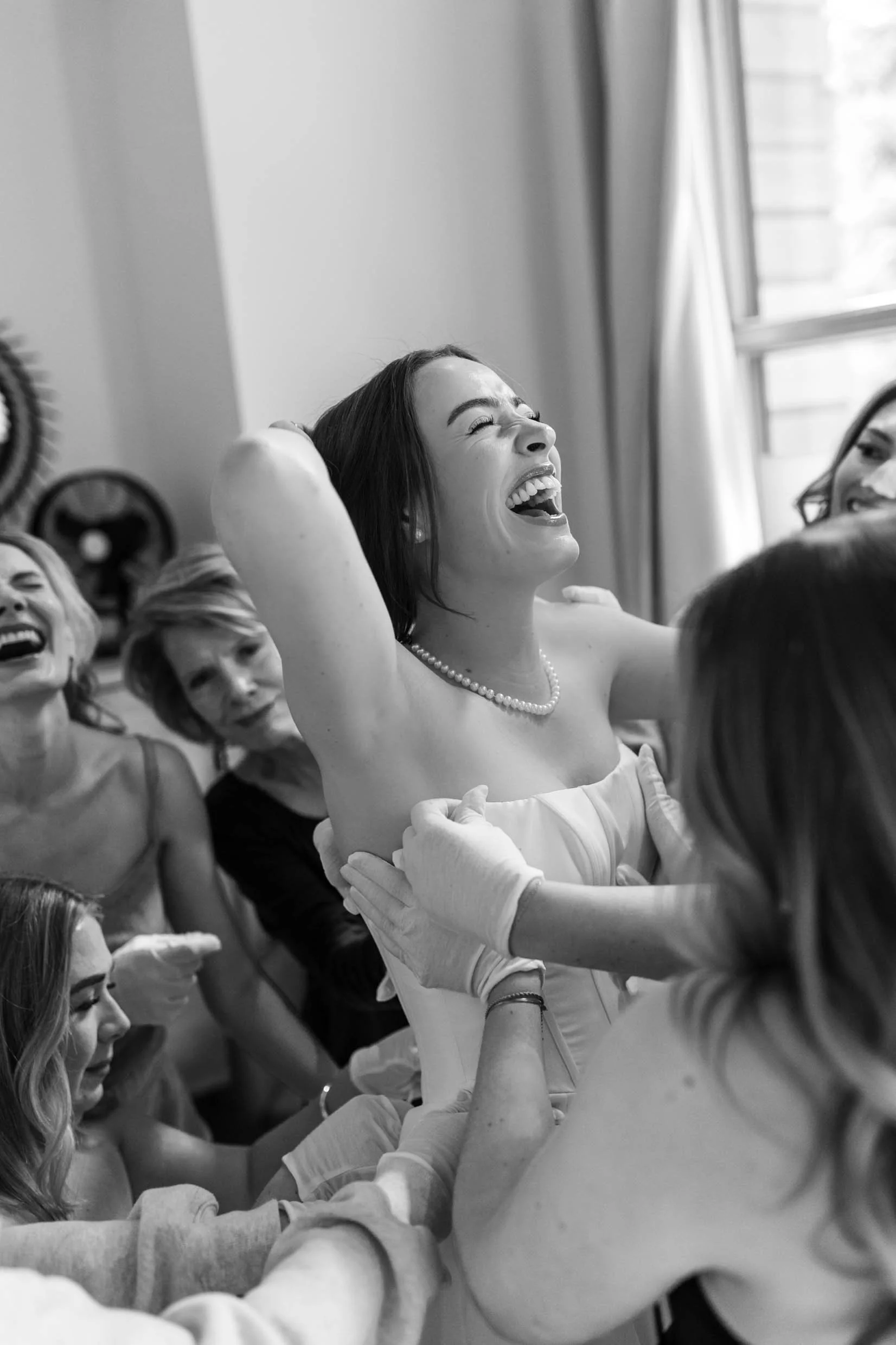 Bride laughs while her bridesmaids help her get into her wedding dress in Banff, Alberta