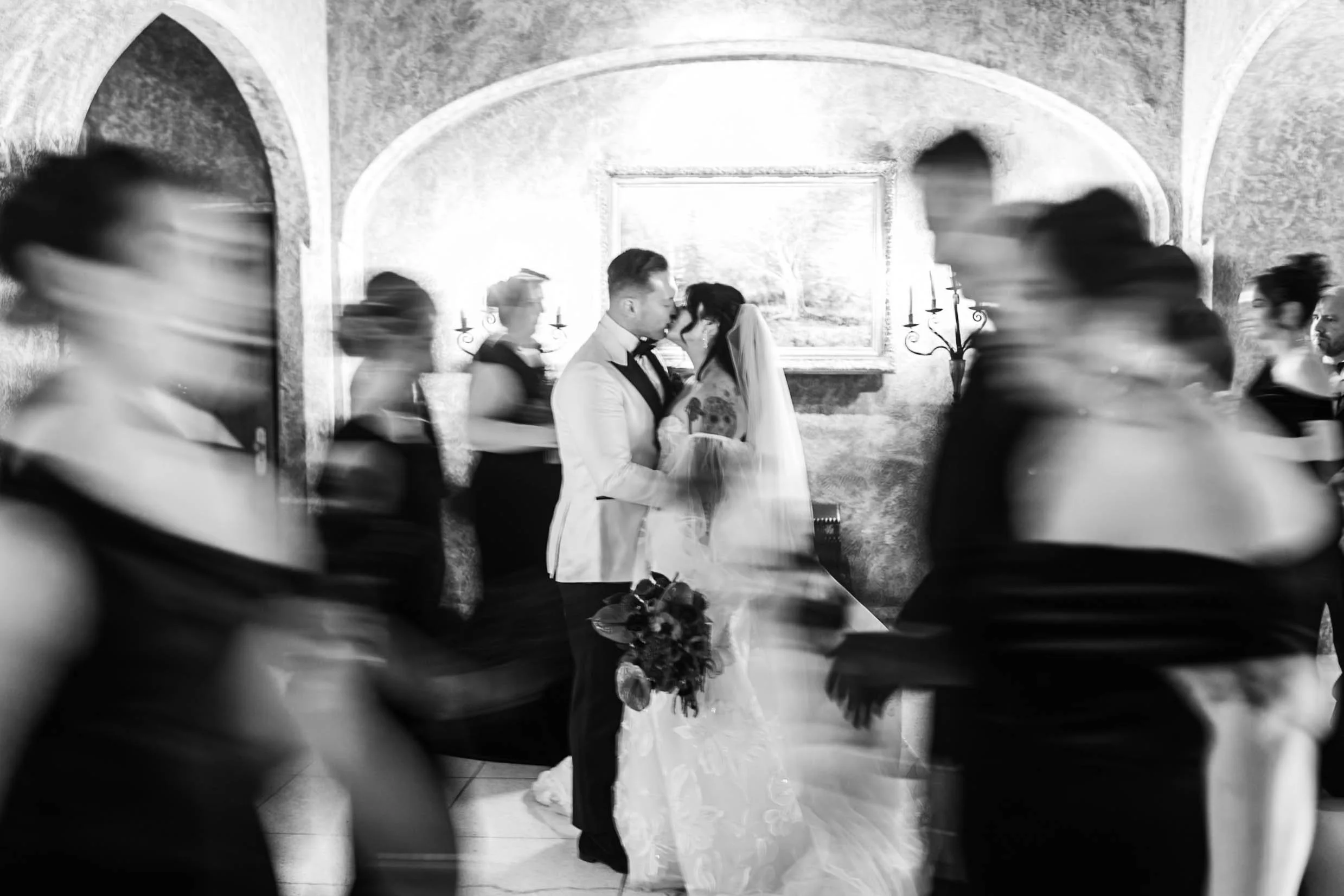 Black and white photo of bridal party part in motion as bride and groom stand still during their wedding at the Banff Springs Hotel