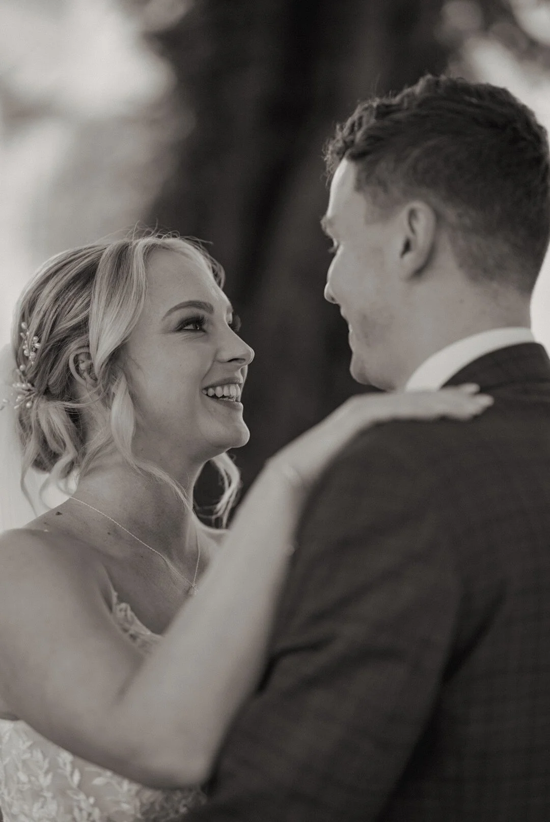 A bride and groom sharing a dance, smiling at each other during their wedding.