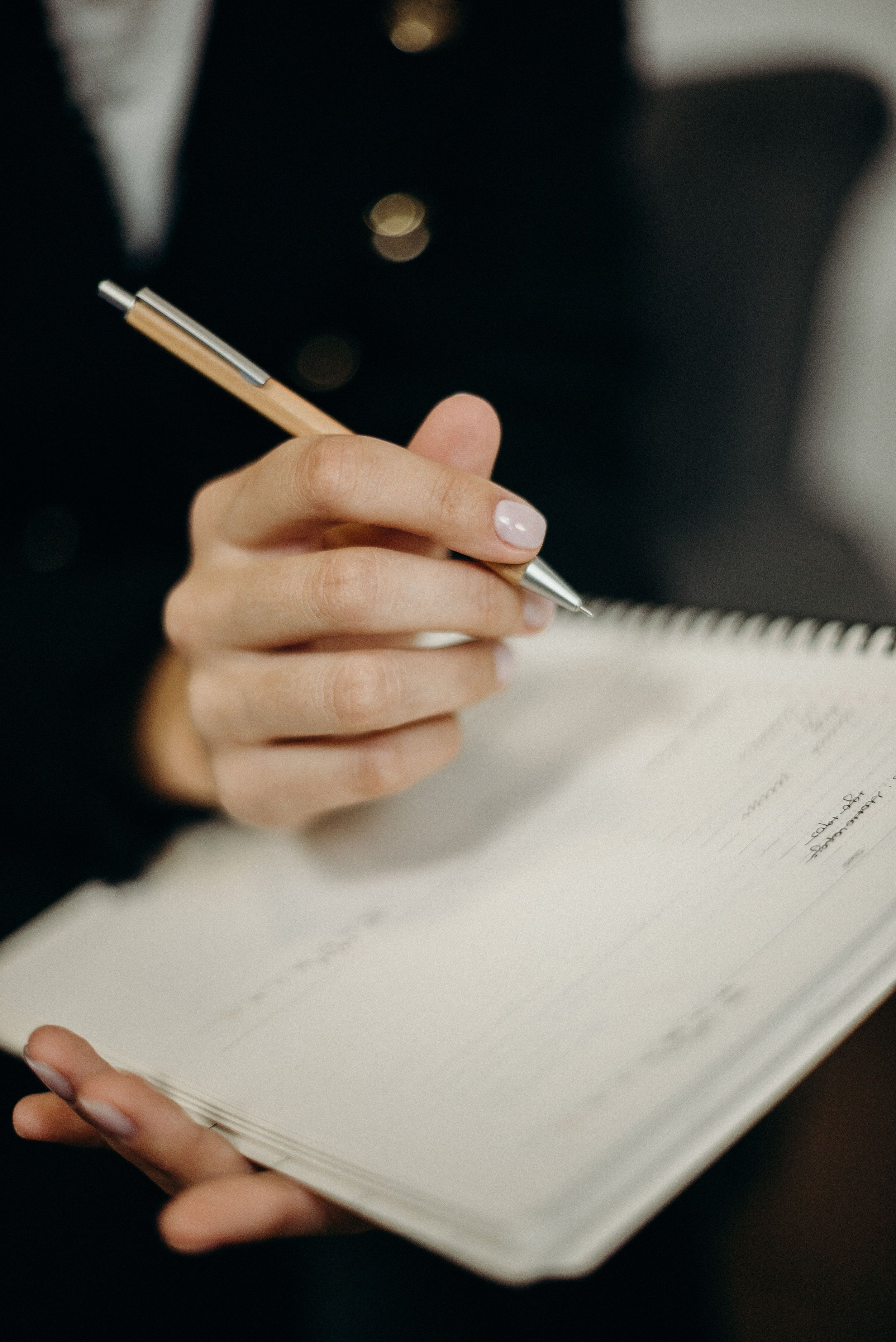 Hand with pen poised over note-book learn about your team take notes northbreak advisors