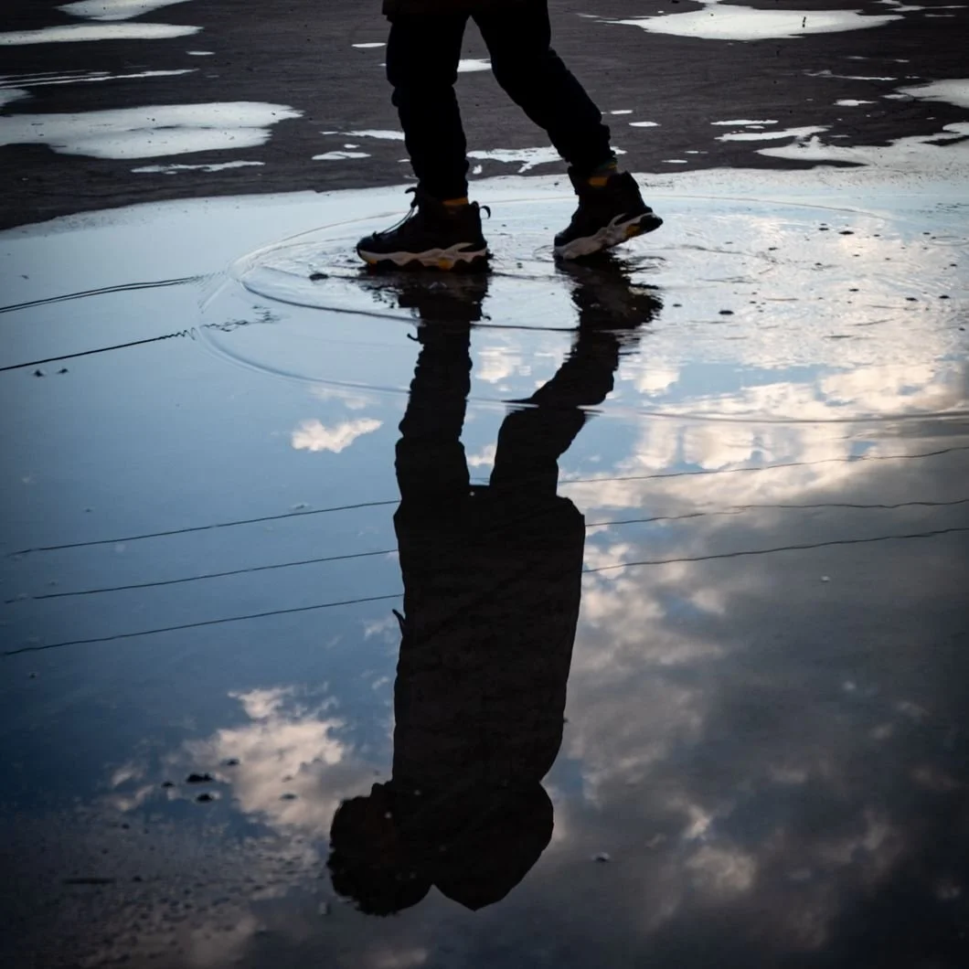 Water Puddle Reflection Of Someone Walking Moody Greys and Blues NorthBreak Advisors