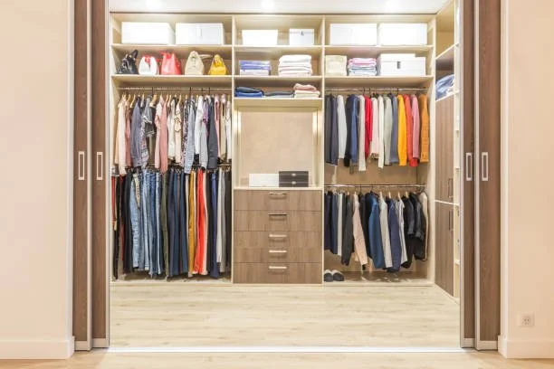 A neatly organized closet with open sliding doors showing shelves, hanging clothes, and storage bins.