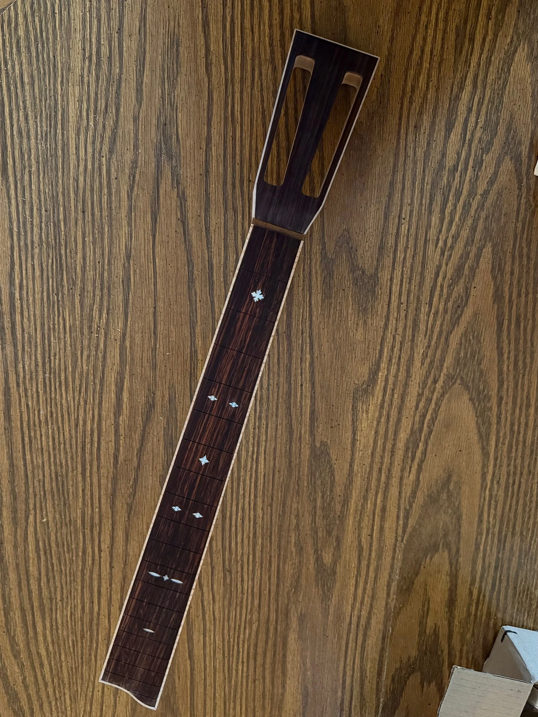Guitar neck-shaped wooden table on a wooden floor.