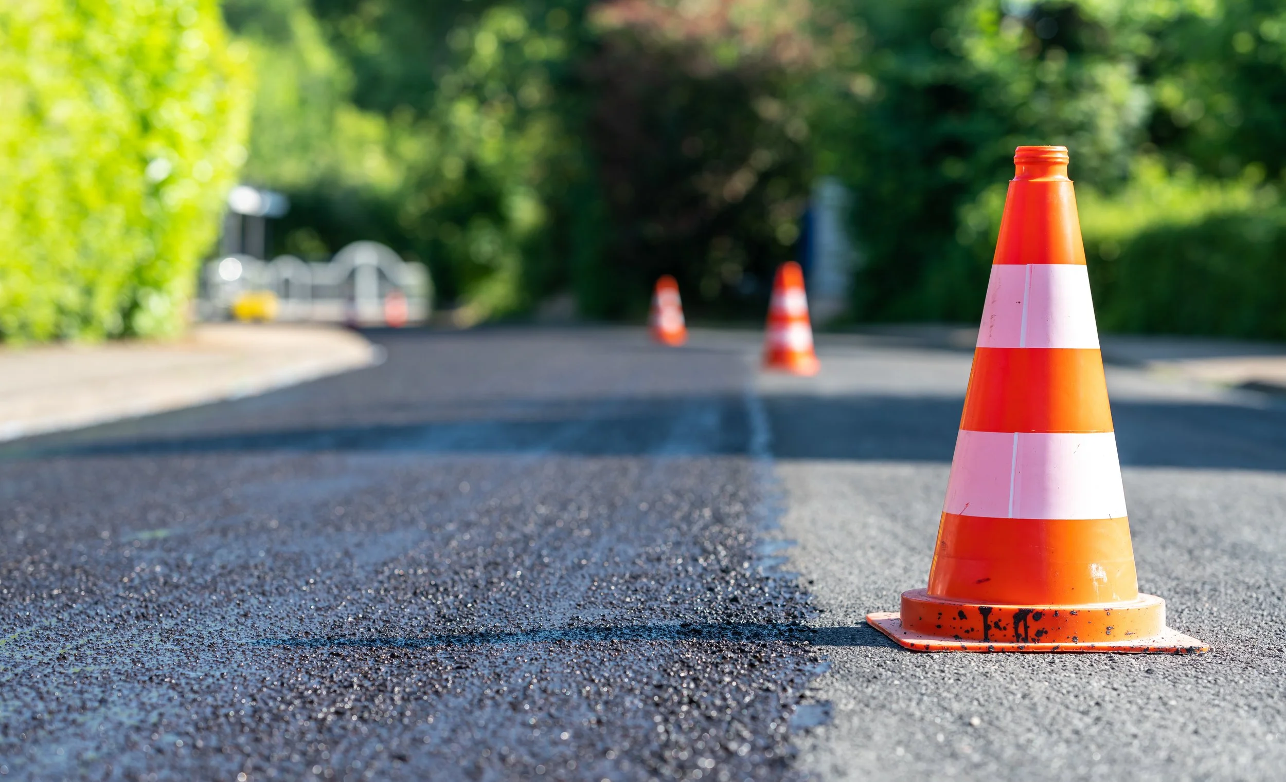 Close-up of an orange traffic cone on an asphalt road with blurred background.